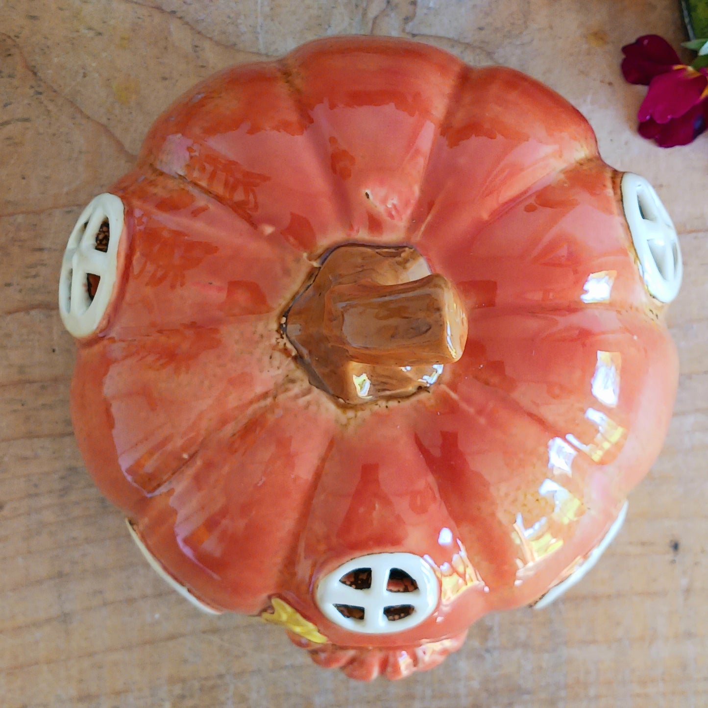 This cute pumpkin house ceramic tealight holder by Village Pottery is the perfect way to create a fun and cosy ambience in your home. Glazed in a beautiful orange hue, it features a rustic brown front door embellished with a heart and three round windows. and the front is decorated with pumpkins and a plant.