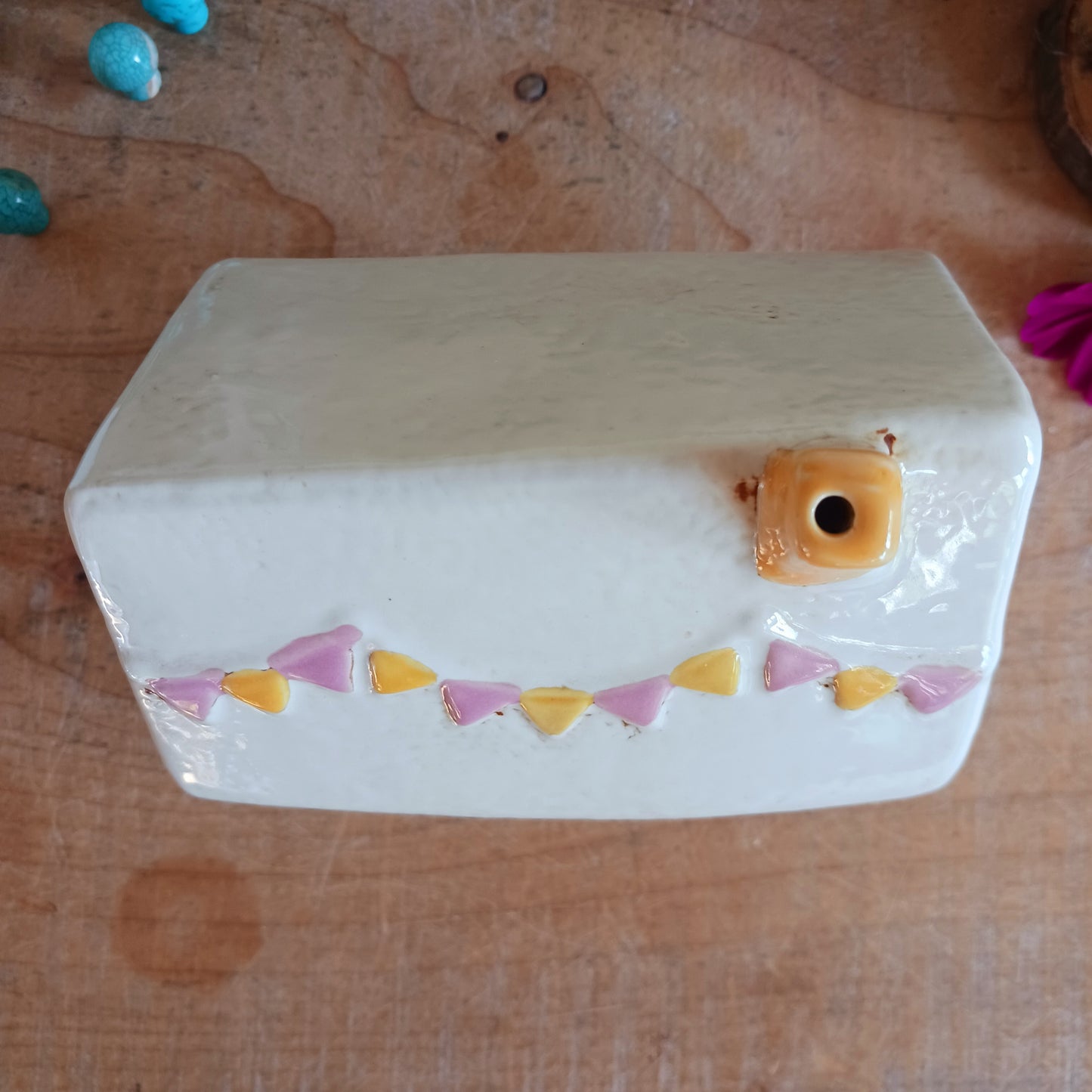 Add a whimsical touch to your décor with the Cards & Gifts Tealight Holder from the Village Pottery Collection. Inspired by the charm of a cozy card shop in a quaint village, this ceramic piece features intricate detailing, from its bunting roof to its delicate windows. Perfect as a tealight holder or simply as a decorative ornament, it brings warmth and character to any space.