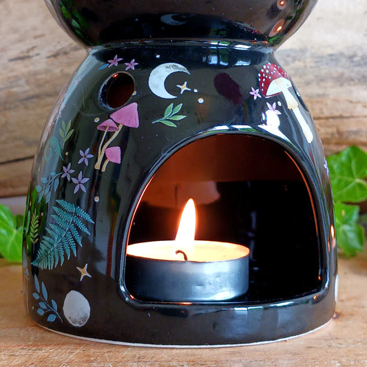 Transform your space into a magical woodland retreat with this beautifully designed dark forest oil burner. Featuring a rich black finish adorned with vibrant illustrations of flora and fauna, this enchanting piece comes to life when lit, casting a warm, ambient glow reminiscent of moonlit nights beneath the stars.