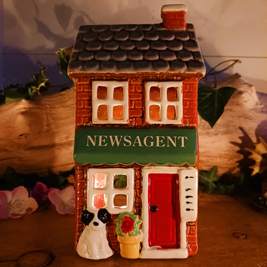Bring a touch of village charm to your home with the Village Pottery Newsagent Tealight Holder. Beautifully designed as a traditional little village newsagent, this charming ceramic tealight holder features a warm red-brick façade, textured cream tiled roof and cheerful bright red front door.