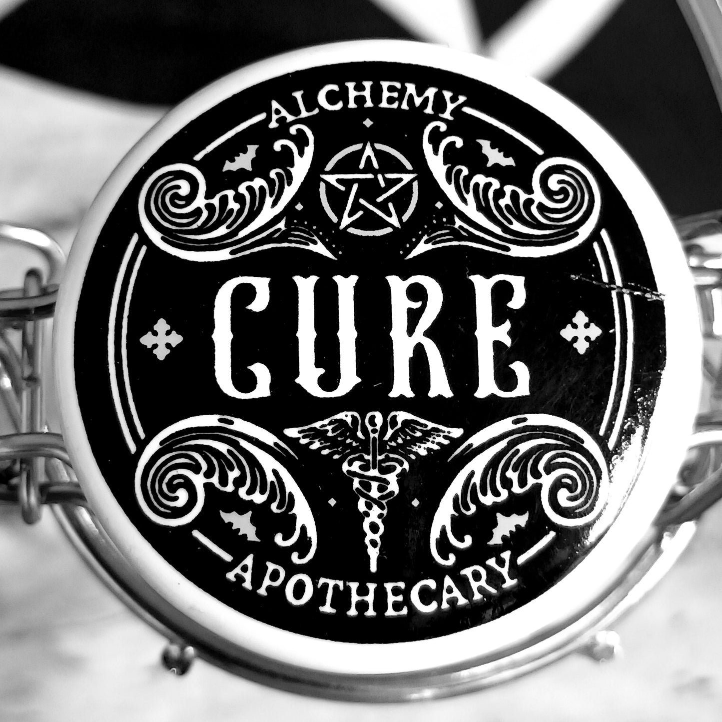 Circular logo with 'Alchemy Cure Apothecary' text and symbols on a black background.
