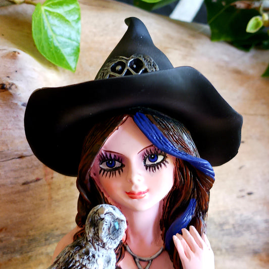 Meet Alvina, a captivating hand-painted witch figurine seated peacefully on a rustic log with her enchanting owl companion. Dressed in a flowing blue gown with long brown hair, Alvina has a mysterious yet charming presence that will appeal to lovers of witches, fantasy and magical décor.