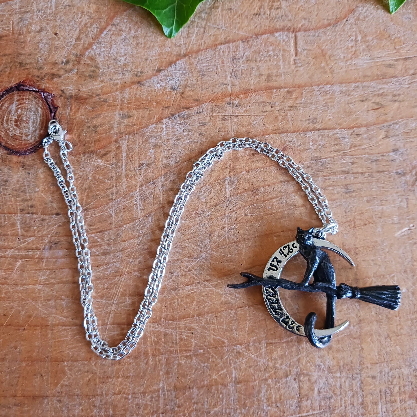 Embrace the magic of the Samhain Sabbat with the Regina Covenorum Necklace. Handcrafted from fine English pewter, this enchanting pendant features a black cat riding a witches’ broom, framed by a polished crescent moon engraved with arcane Theban symbols. Perfect for lovers of mystical jewellery, witchcraft, and celestial-inspired designs, this necklace celebrates the mysterious bond between a witch and her familiar.