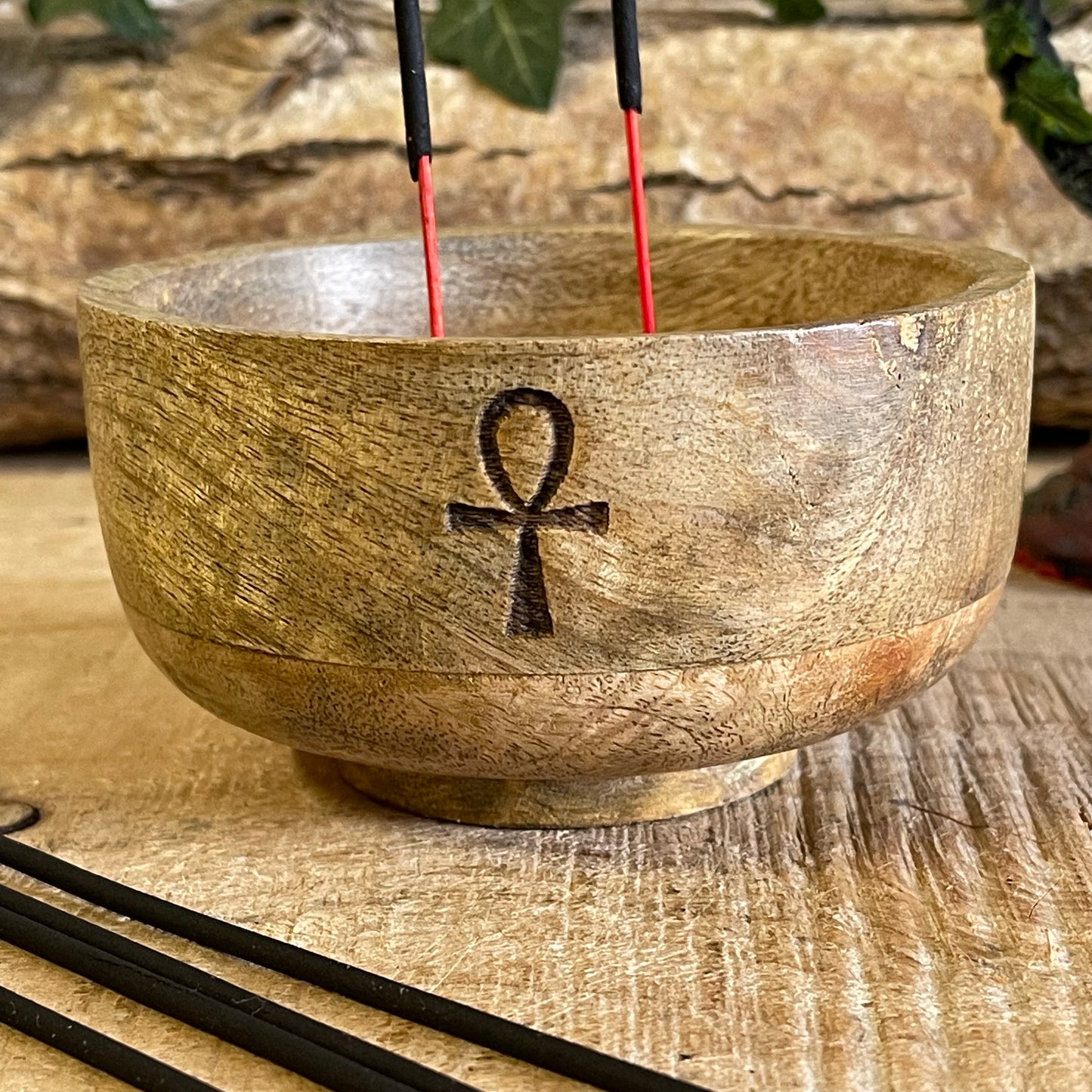 This incense holder is a compact, handcrafted wooden bowl, measuring approximately 11 cm in diameter and 6 cm in height. It features an engraving of the Ankh, also known as the Key of Life, a symbol associated with life and protection in ancient Egyptian culture. The Ankh etching adds a mystical and meaningful touch to the piece, blending spirituality with functionality.

The design accommodates both incense sticks and incense cones. The bowl is likely shaped to safely catch ash, with designated holders or 