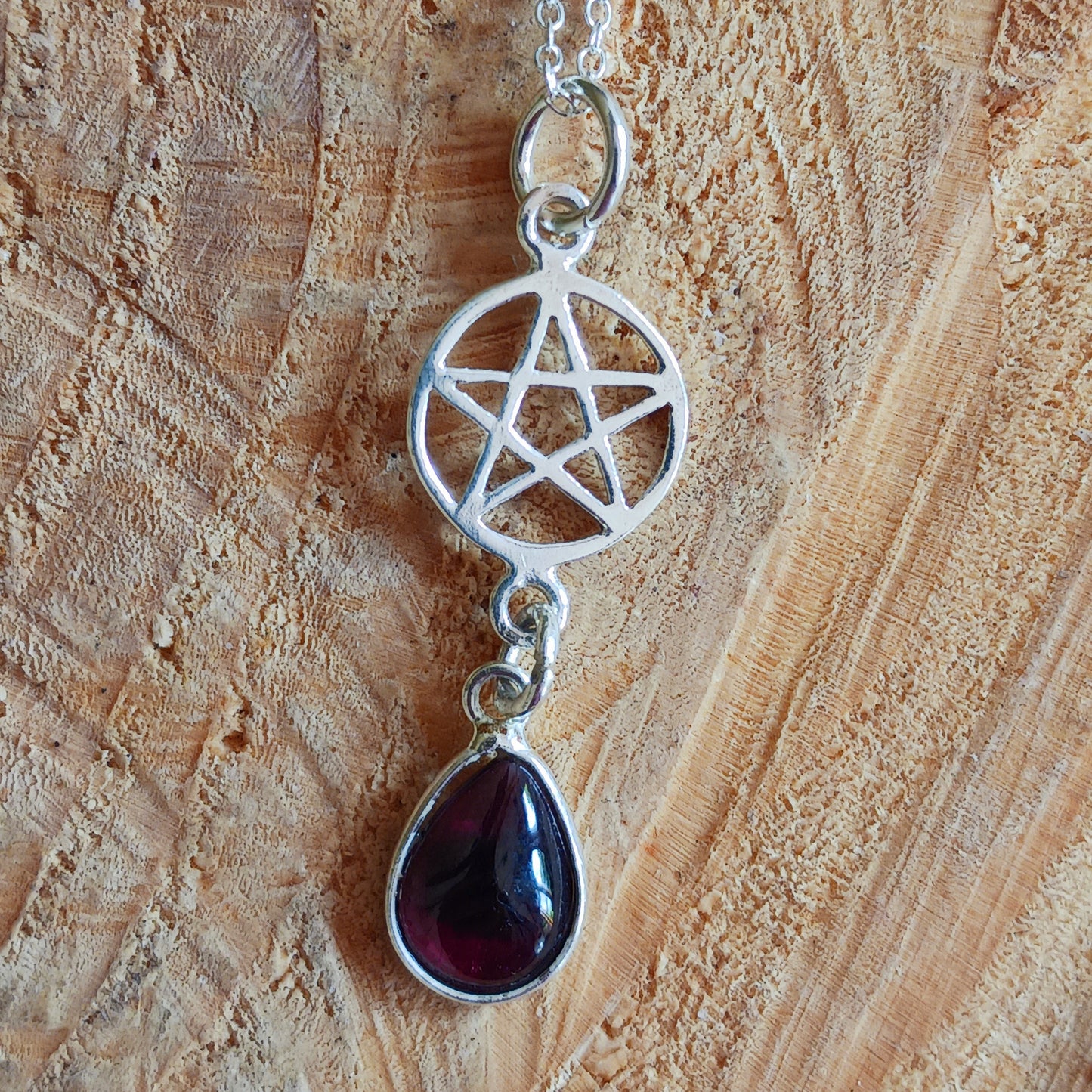 Beautifully handcrafted pentagram pendant in solid silver with a teardrop Garnet gemstone.&nbsp;&nbsp;   According to the Greek mathematician and philosopher Pythagoras, the pentagram&nbsp;represents the elements: Earth, Air, Fire and Water, with Spirit placed on the top. His followers, the Pythagoreans, saw it as mathematical perfection, which would later come to be known as the Golden ratio.