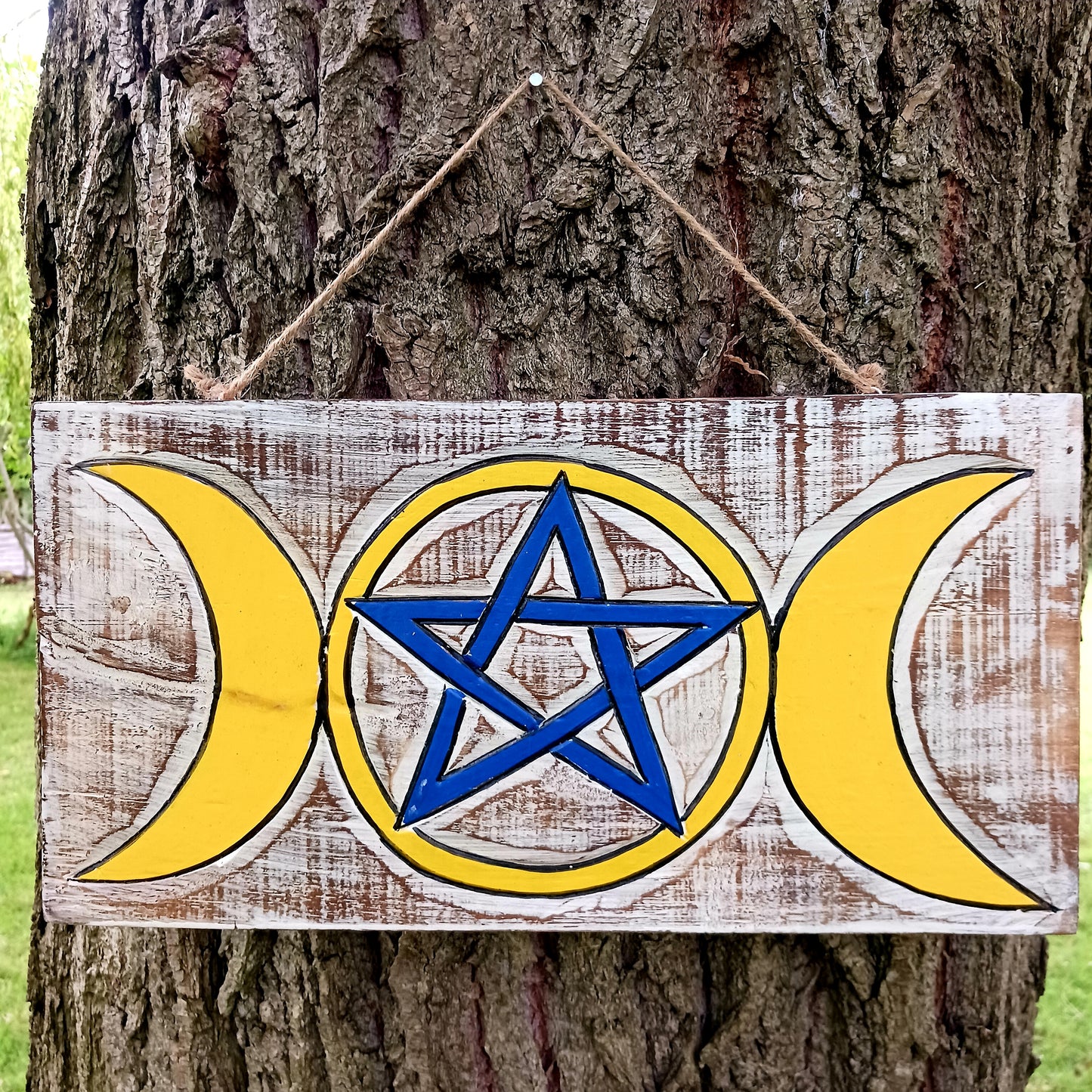 This cool wall plaque has a white wash effect with vibrant hand painted design featuring the triple goddess and pentacle symbols.&nbsp;  This lovely plaque comes with thick twine for easy hanging, perfect for any wall or door.