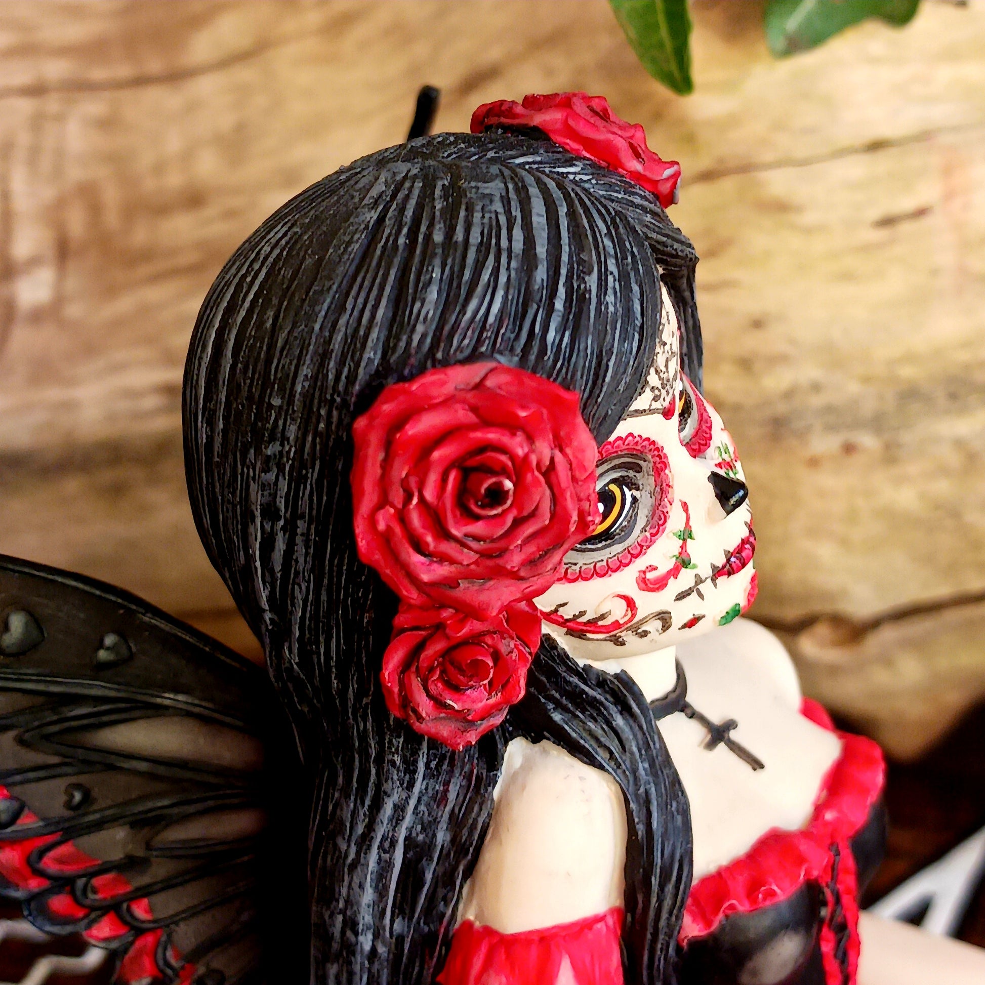 This stunning Fairy, Rosalia, was created by Fantasy brand Nemesis Now. She innocently sits with her striped legs extended to the side, wearing a black corseted dress that has a red skirt detailed with black roses.