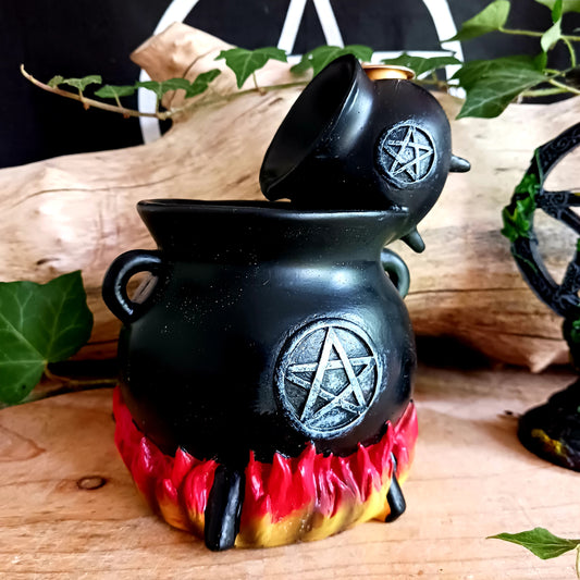 Place a backflow incense cone on top of this resin cauldron burner and watch the smoke&nbsp; gently pour between cauldrons. This burner is accented by flames at the bottom and a distressed silver-effect pentagram design.&nbsp; Finished with a light to create an outstanding smoke effect. Both fun and mesmerizing to watch!