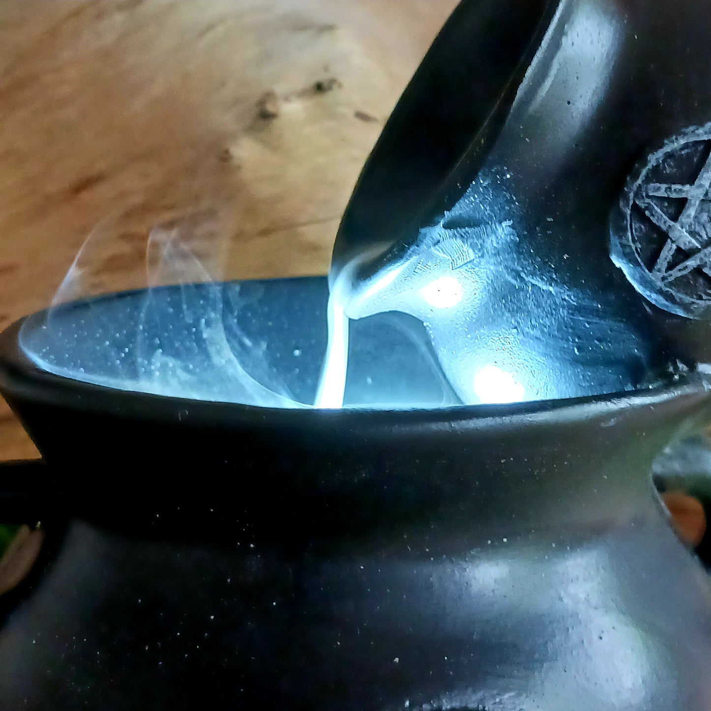 Place a backflow incense cone on top of this resin cauldron burner and watch the smoke&nbsp; gently pour between cauldrons. This burner is accented by flames at the bottom and a distressed silver-effect pentagram design.&nbsp; Finished with a light to create an outstanding smoke effect. Both fun and mesmerizing to watch!