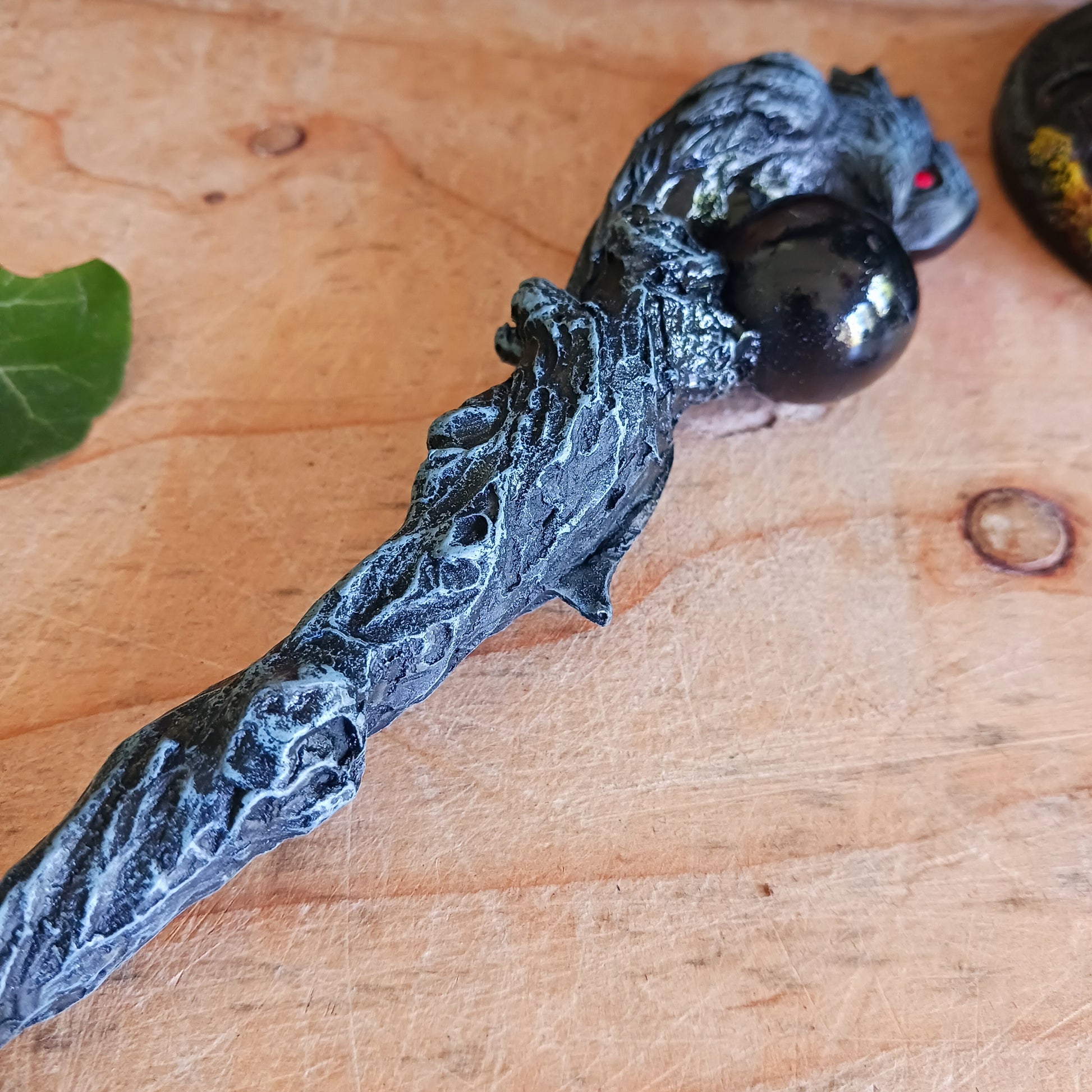 Immerse yourself in the world of witchcraft and wizardry with this impressive red-eyed dark grey raven wand, featuring a captivating black sphere – a true masterpiece that stands out in every magical collection.