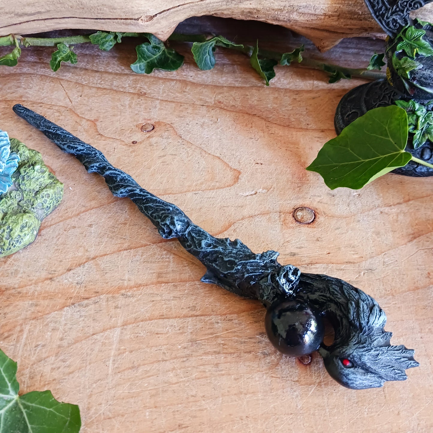 Immerse yourself in the world of witchcraft and wizardry with this impressive red-eyed dark grey raven wand, featuring a captivating black sphere – a true masterpiece that stands out in every magical collection.