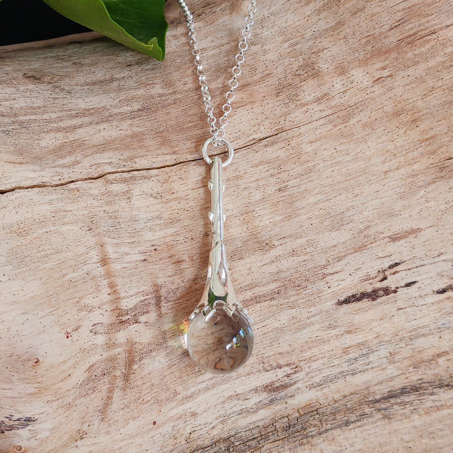 This Crystal Ball and Wand Pendant is made with with exquisite detail, featuring a 925 Sterling Silver Scrying Wand and a clear Quartz Crystal Ball.&nbsp; The clear Quartz Crystal Ball is set in sterling silver which has been carved in places to allow the light to shine down through the wand to give the ball more clarity.