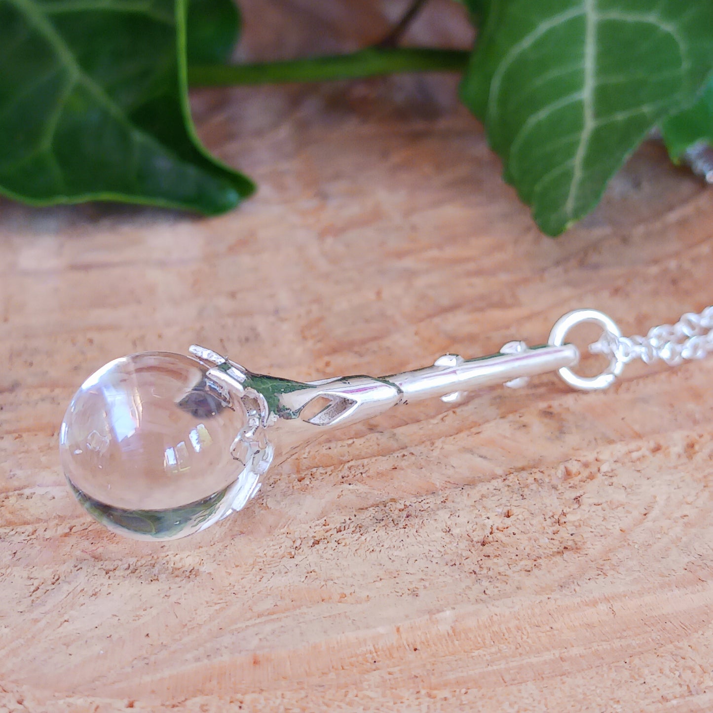 This Crystal Ball and Wand Pendant is made with with exquisite detail, featuring a 925 Sterling Silver Scrying Wand and a clear Quartz Crystal Ball.&nbsp; The clear Quartz Crystal Ball is set in sterling silver which has been carved in places to allow the light to shine down through the wand to give the ball more clarity.