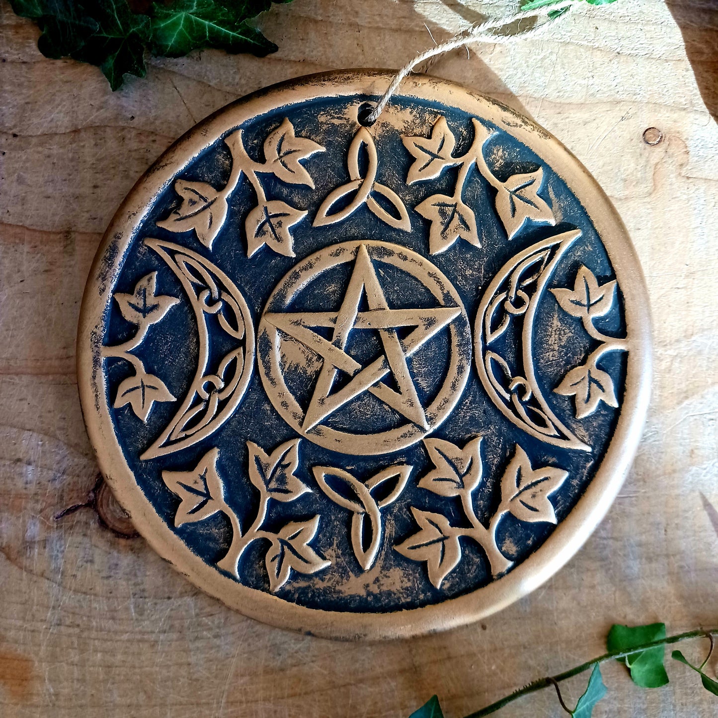 The plaque depicts a triple moon design also referred to as the triple goddess. The symbol represents the Maiden, Mother and Crone as the waxing, full and waning moon and is often related to feminine energy and psychic abilities.