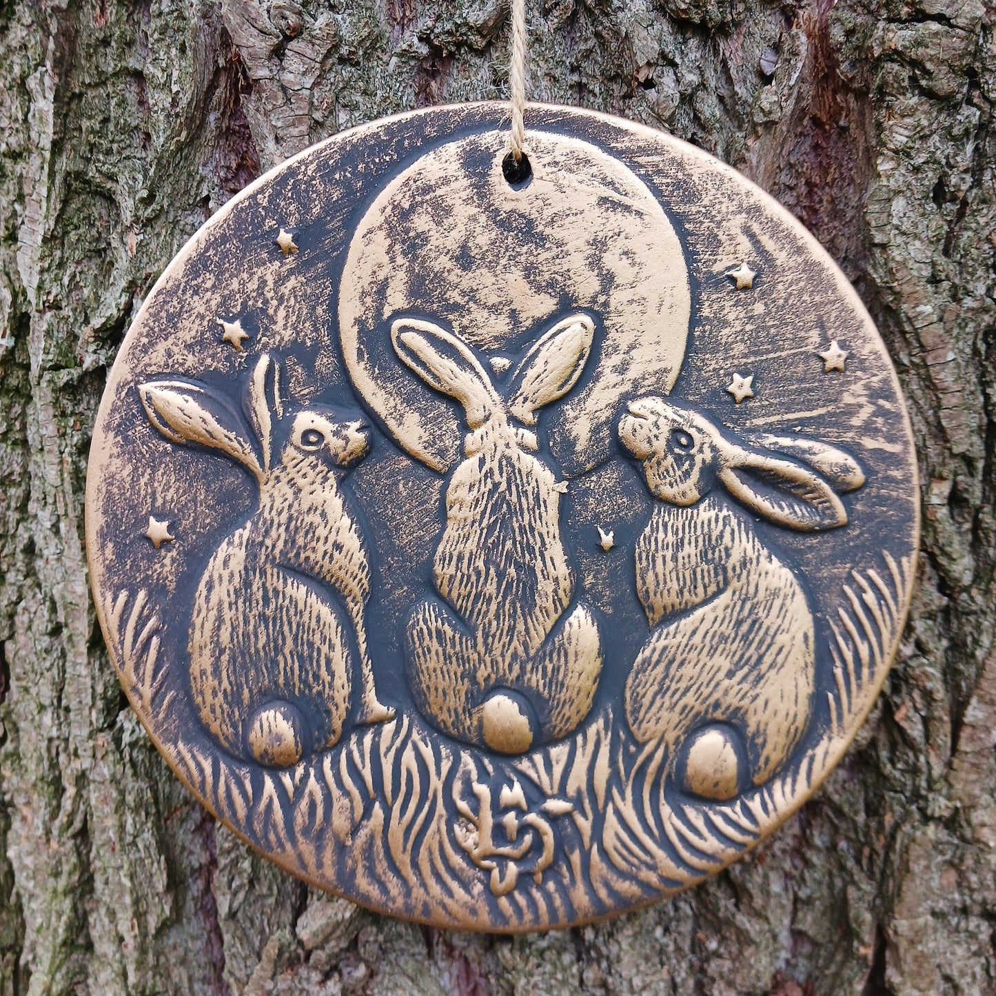 A stunning terracotta wall plaque with a bronze-like effect and striking motif of three moon-gazing hares. This symbol is commonly used to represent fertility and growth. Perfect for garden decor.