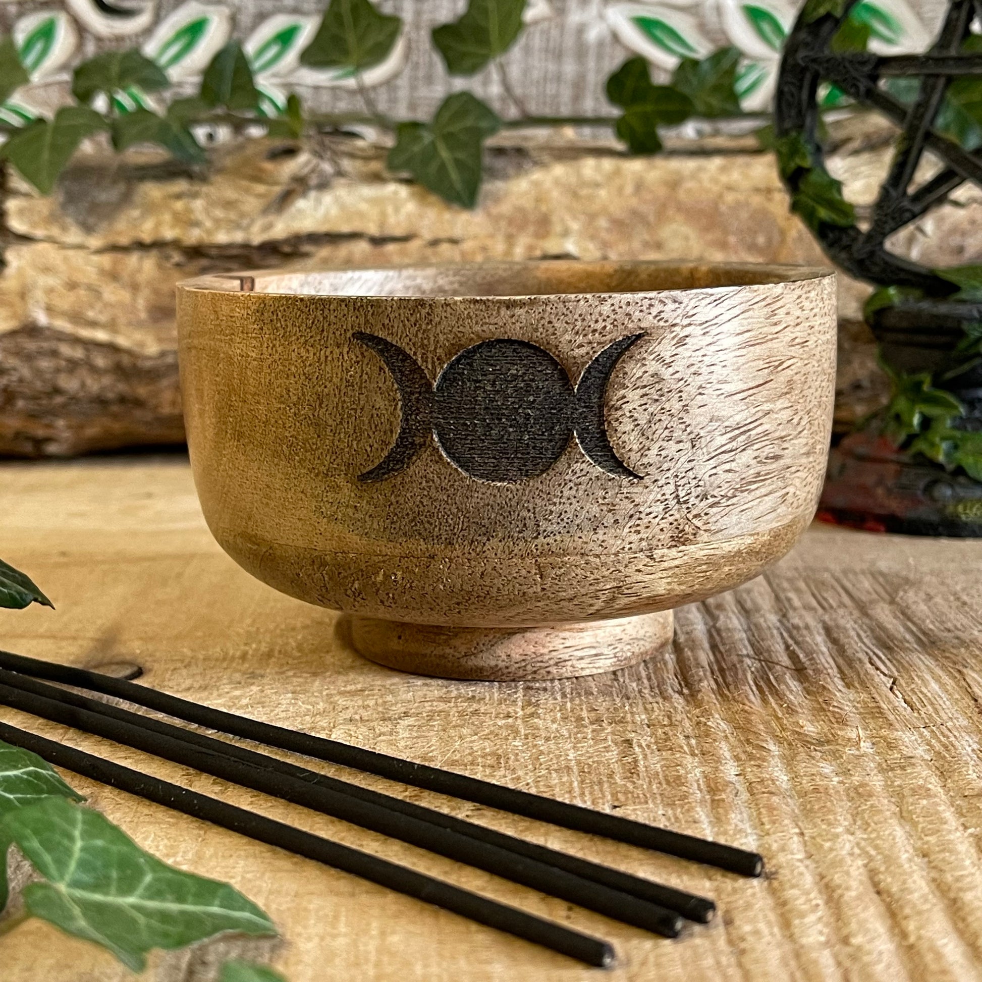 This incense holder is a compact and beautifully crafted wooden bowl measuring 11 cm in diameter and 6 cm in height. Its design features the Triple Moon symbol, representing the phases of the moon: waxing, full, and waning. This symbol is etched into the wood, giving it a subtle yet mystical appeal, which is often associated with spiritual growth, intuition, and the goddess in many traditions.