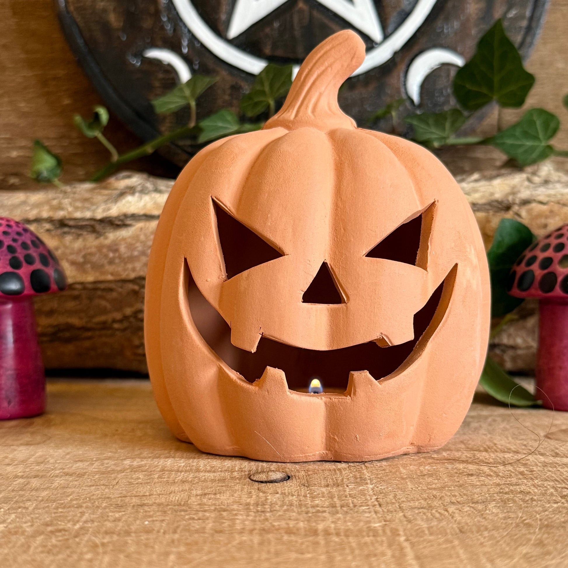 From Buddha Moon, this 12.5cm terracotta pumpkin ornament is the perfect addition to your Halloween décor. Featuring a classic jack-o’-lantern design, it holds a tealight candle to cast a spooky, warm glow indoors or outdoors. Ideal for mantels, tables, patios, or garden displays, this pumpkin combines traditional craftsmanship with festive charm. Durable and stylish, it enhances your Halloween celebrations year after year.