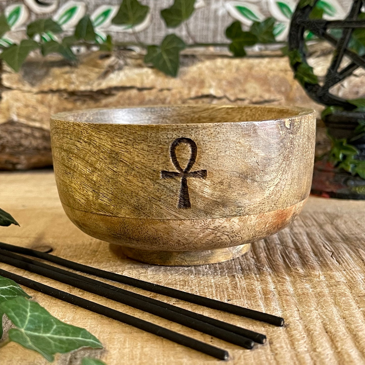 This incense holder is a compact, handcrafted wooden bowl, measuring approximately 11 cm in diameter and 6 cm in height. It features an engraving of the Ankh, also known as the Key of Life, a symbol associated with life and protection in ancient Egyptian culture. The Ankh etching adds a mystical and meaningful touch to the piece, blending spirituality with functionality.

The design accommodates both incense sticks and incense cones. The bowl is likely shaped to safely catch ash, with designated holders or 