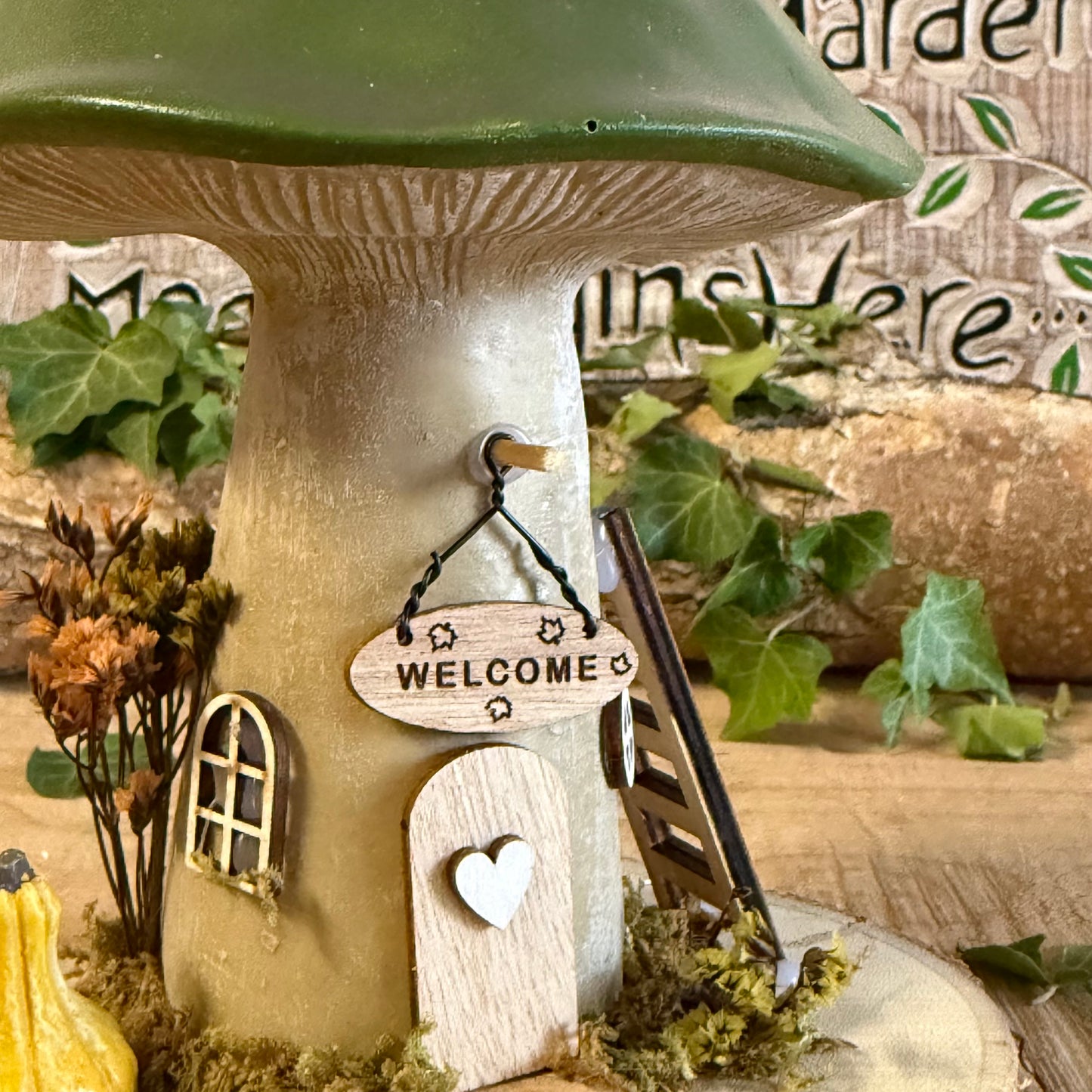 Welcome all who wander with this charming Folk Art Mushroom Cottage with Welcome Sign (Large) — a beautifully hand painted fairy house inspired by woodland folklore and cosy forest living. Its bright toadstool roof, delicate floral detailing, and rustic textures create the feeling of a tiny cottage nestled beneath ancient trees.