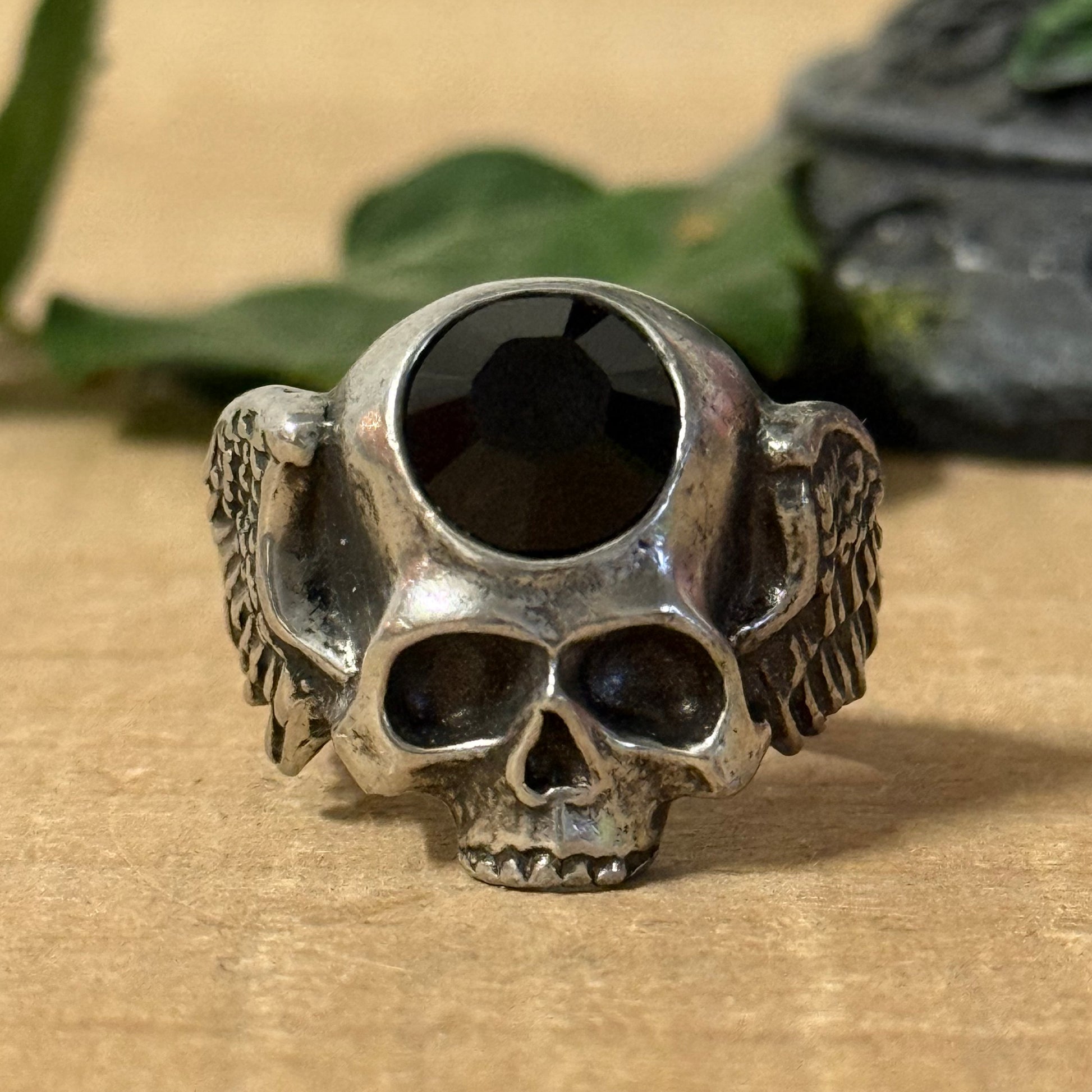 Invoke the balance of strength and spiritual awareness with the Alchemy Gothic Skull and Wings Ring. Crafted from durable black pewter, this ring showcases a detailed skull with outstretched wings, embodying transformation, mortality, and the freedom of the soul.

An embossed black stone rests at its heart, radiating grounding energy and mindfulness. This gothic accessory merges elegance with spiritual symbolism, making it ideal for those who seek both style and contemplation.

Designed to fit size U, this 