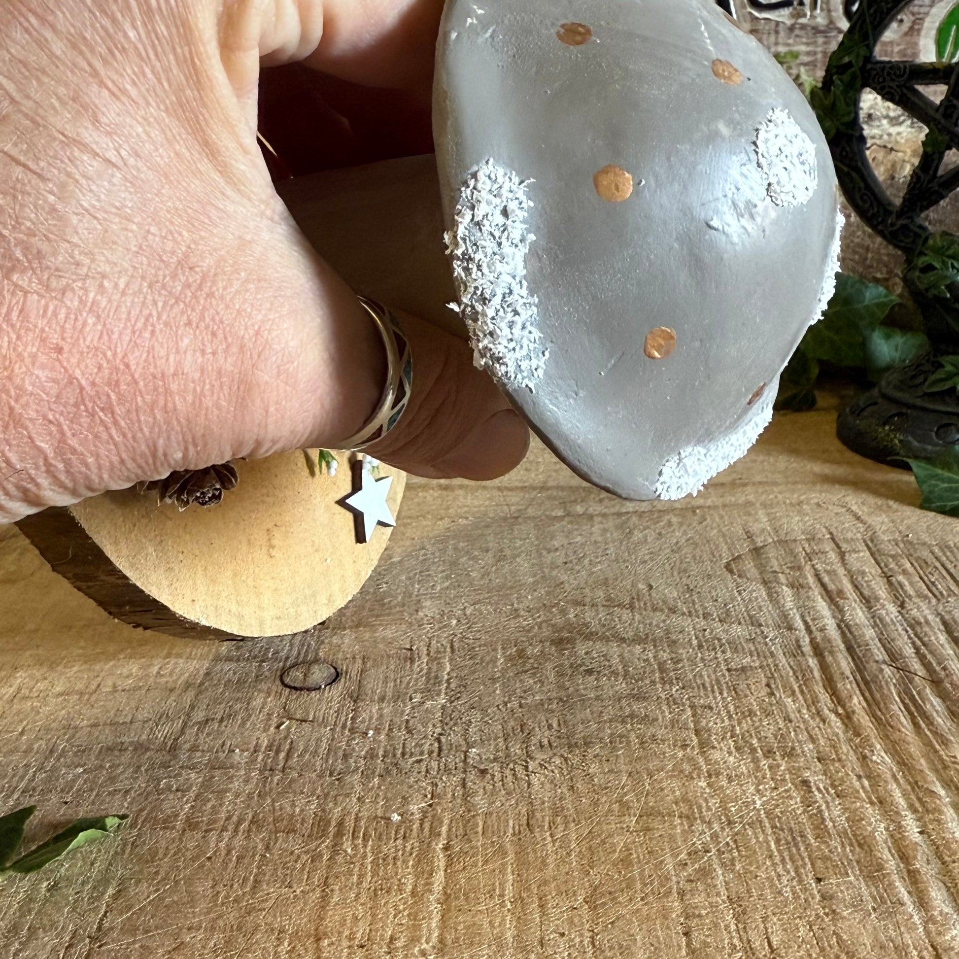 Hand holding a textured stone with gold specks on a wooden surface