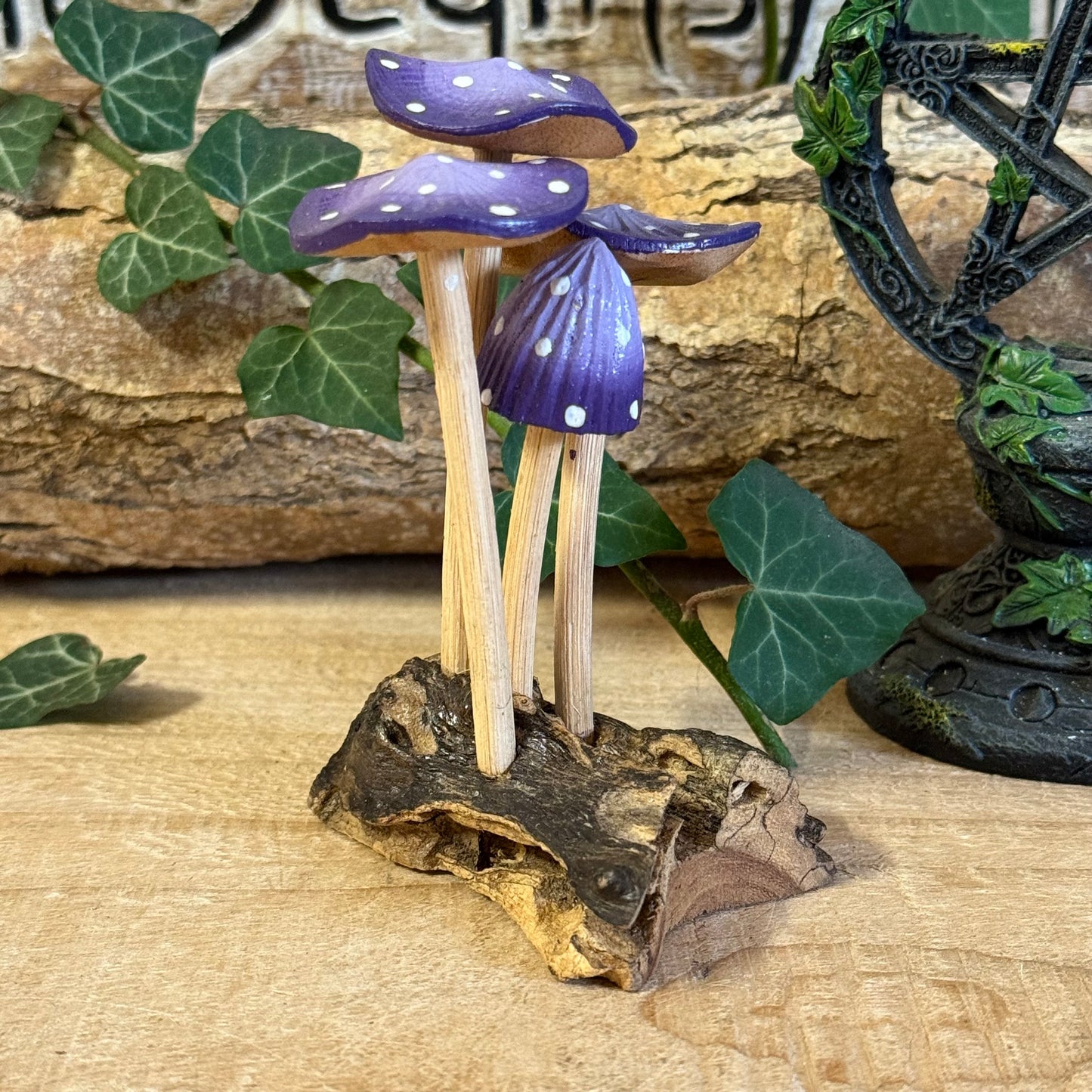 Hand carved purple wooden mushrooms on rustic base. Perfect fairy home or cottage-style décor, adding whimsical woodland charm to any space.