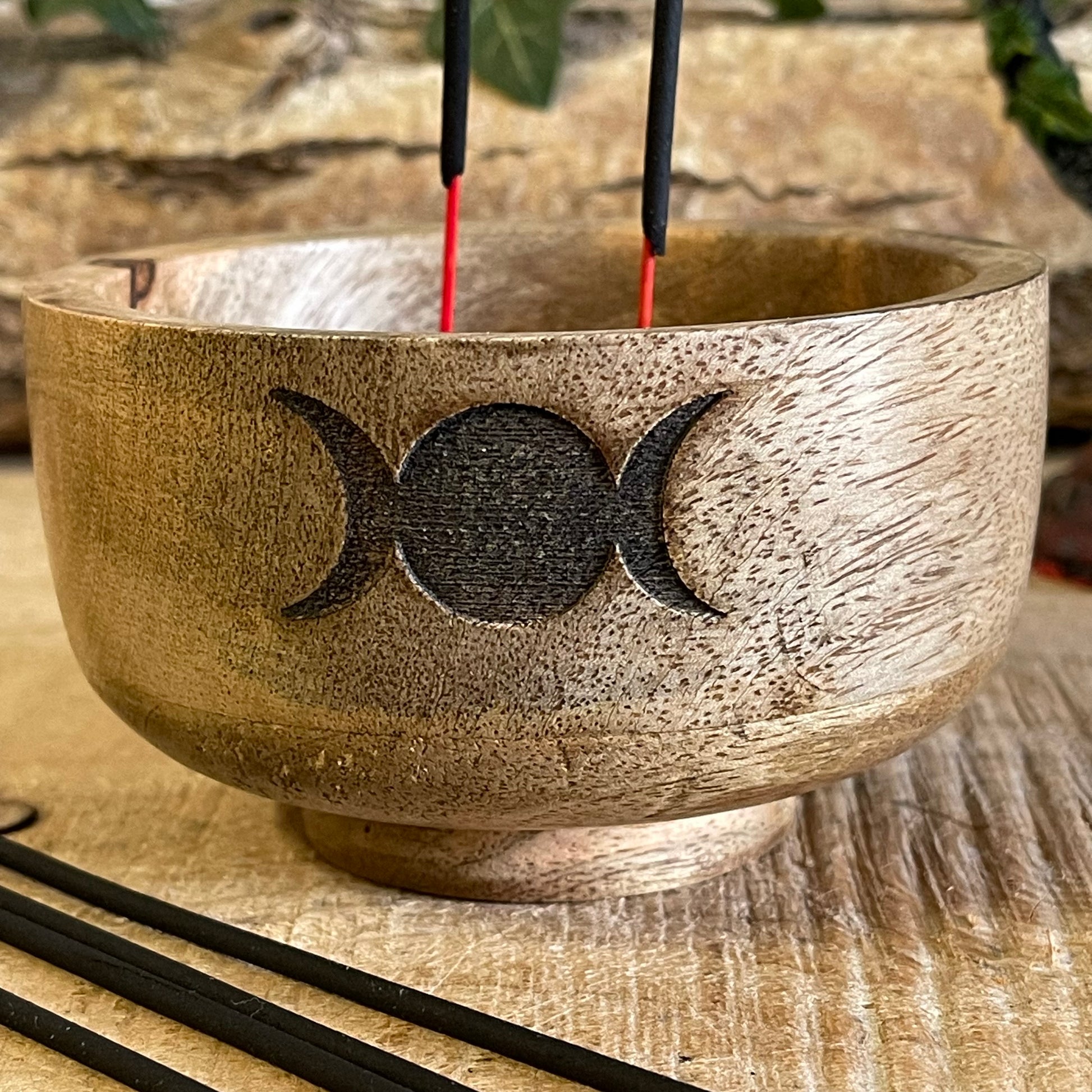 This incense holder is a compact and beautifully crafted wooden bowl measuring 11 cm in diameter and 6 cm in height. Its design features the Triple Moon symbol, representing the phases of the moon: waxing, full, and waning. This symbol is etched into the wood, giving it a subtle yet mystical appeal, which is often associated with spiritual growth, intuition, and the goddess in many traditions.