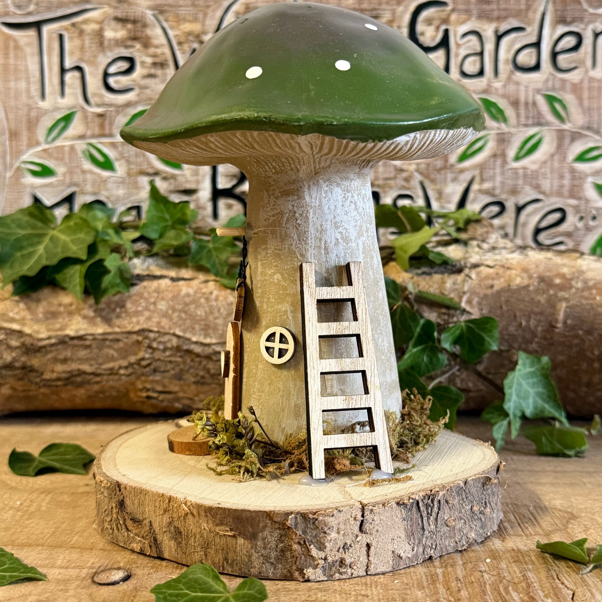 Welcome all who wander with this charming Folk Art Mushroom Cottage with Welcome Sign (Large) — a beautifully hand painted fairy house inspired by woodland folklore and cosy forest living. Its bright toadstool roof, delicate floral detailing, and rustic textures create the feeling of a tiny cottage nestled beneath ancient trees.