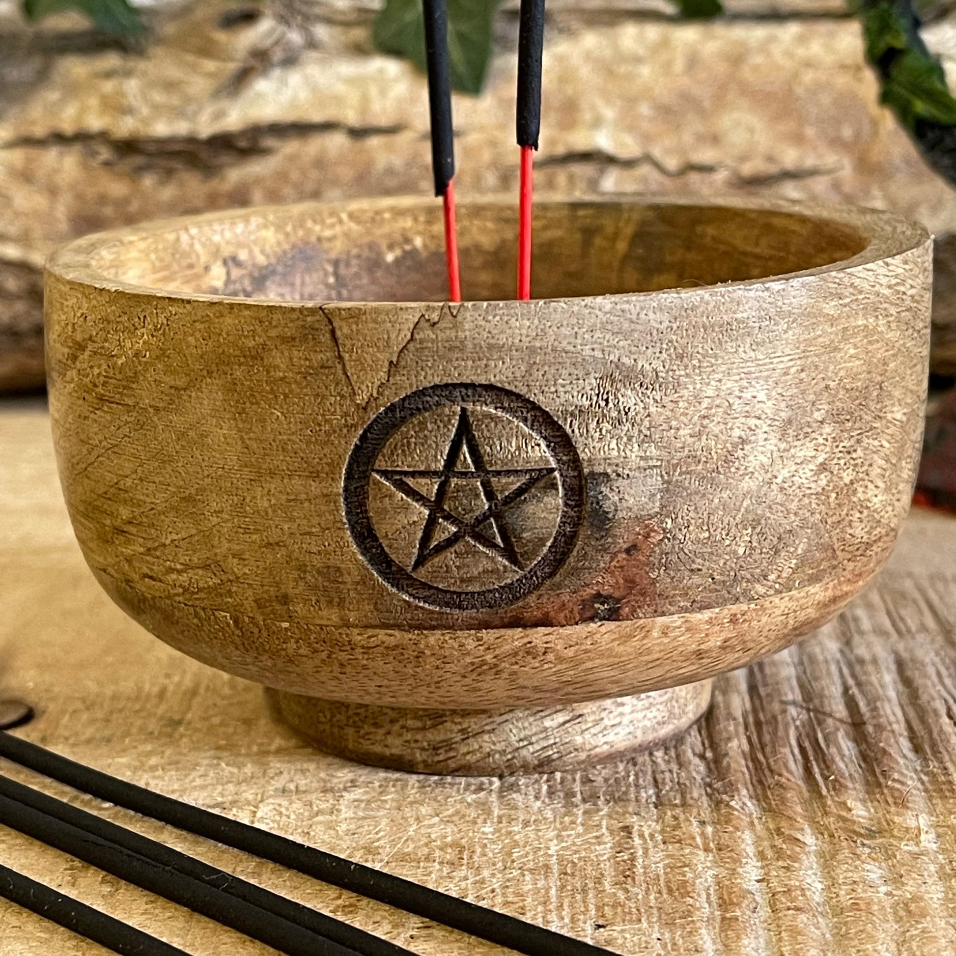 This incense holder is a compact, handcrafted wooden bowl with a rustic charm. Measuring 11 cm in diameter and 6 cm in height, it is designed to hold both incense sticks and cones. The highlight of this piece is the pentacle symbol, carefully etched onto the inside of the bowl, which adds a mystical, spiritual touch. The pentacle, often associated with protection and the elements, makes it ideal for meditation or ritualistic practices. The wood’s natural grain adds an earthy texture, enhancing its aesthetic