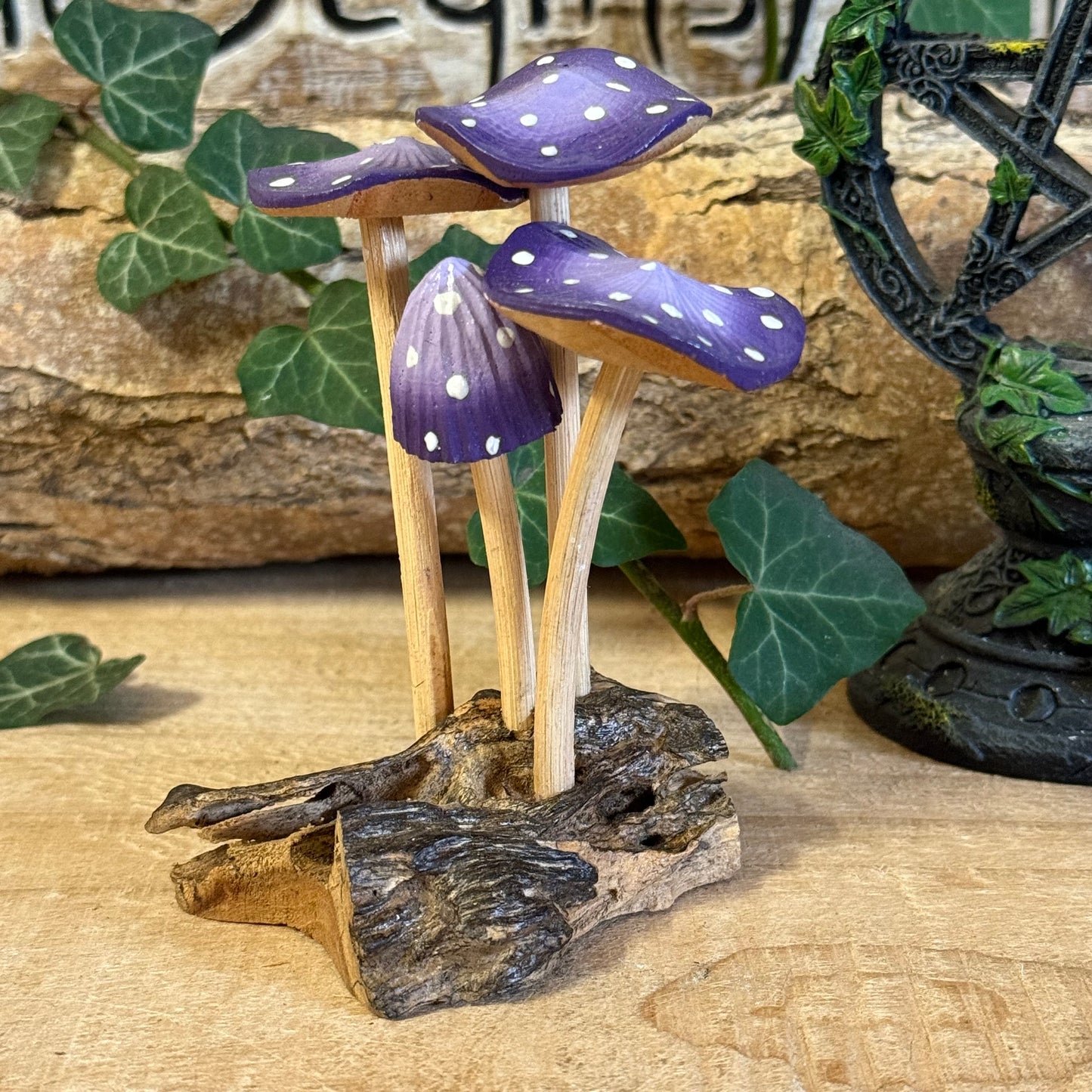 Hand carved purple wooden mushrooms on rustic base. Perfect fairy home or cottage-style décor, adding whimsical woodland charm to any space.