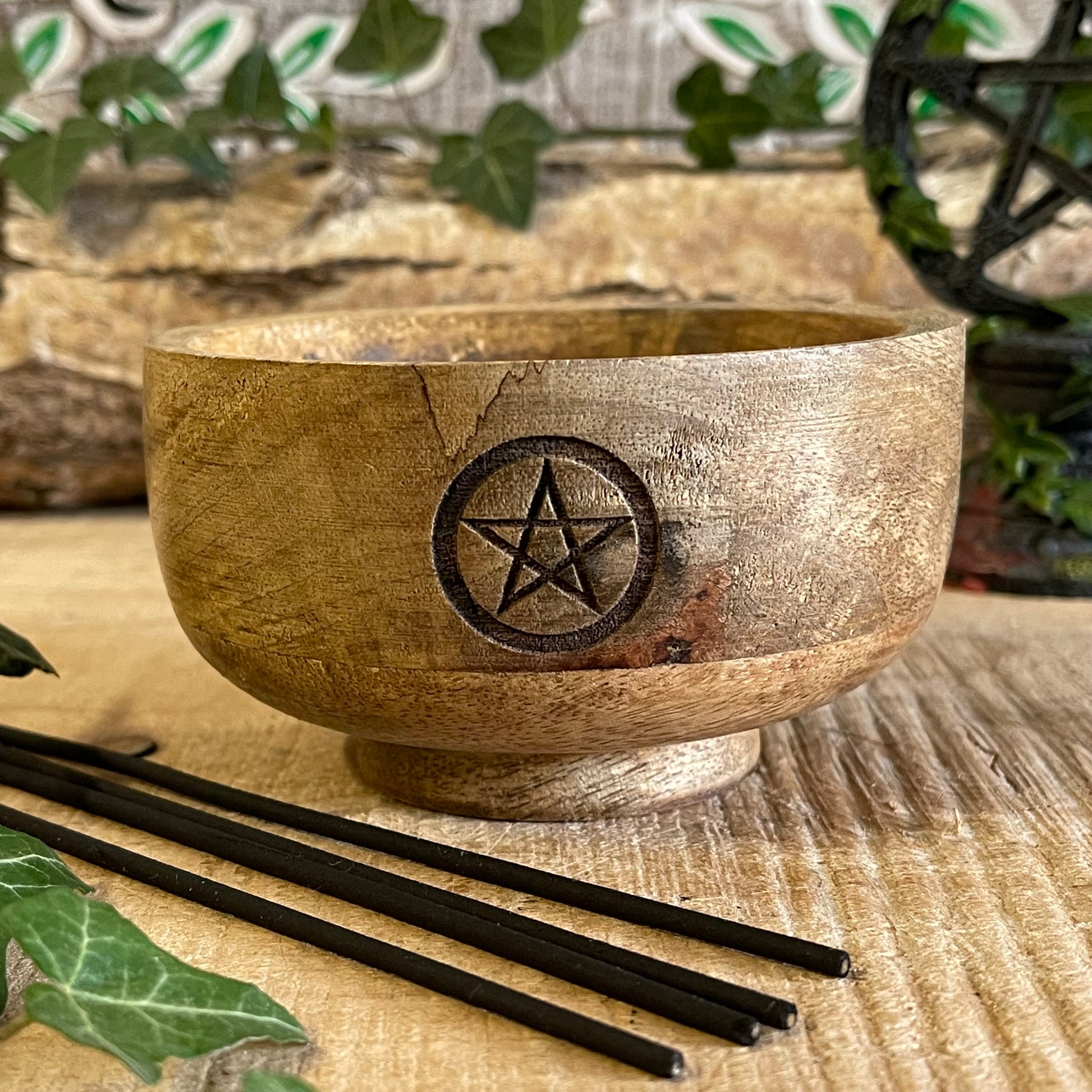 This incense holder is a compact, handcrafted wooden bowl with a rustic charm. Measuring 11 cm in diameter and 6 cm in height, it is designed to hold both incense sticks and cones. The highlight of this piece is the pentacle symbol, carefully etched onto the inside of the bowl, which adds a mystical, spiritual touch. The pentacle, often associated with protection and the elements, makes it ideal for meditation or ritualistic practices. The wood’s natural grain adds an earthy texture, enhancing its aesthetic