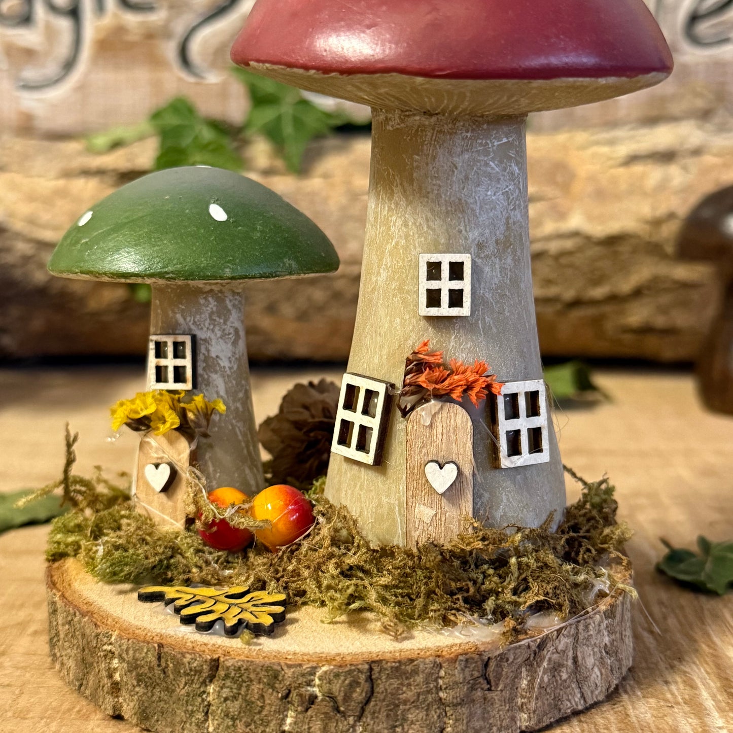 Wander into a whimsical woodland with our Folk Art Mushroom Two Cottages (Tall) — a delightful pair of hand painted fairy houses inspired by rustic village life and the charm of springtime meadows. Each tall mushroom cottage is adorned with bright folk art patterns, floral details, and earthy tones that bring a sense of storybook enchantment to your home.