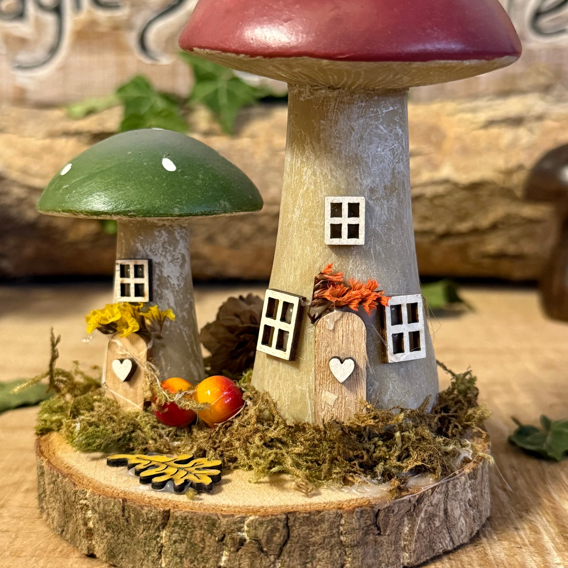 Wander into a whimsical woodland with our Folk Art Mushroom Two Cottages (Tall) — a delightful pair of hand painted fairy houses inspired by rustic village life and the charm of springtime meadows. Each tall mushroom cottage is adorned with bright folk art patterns, floral details, and earthy tones that bring a sense of storybook enchantment to your home.