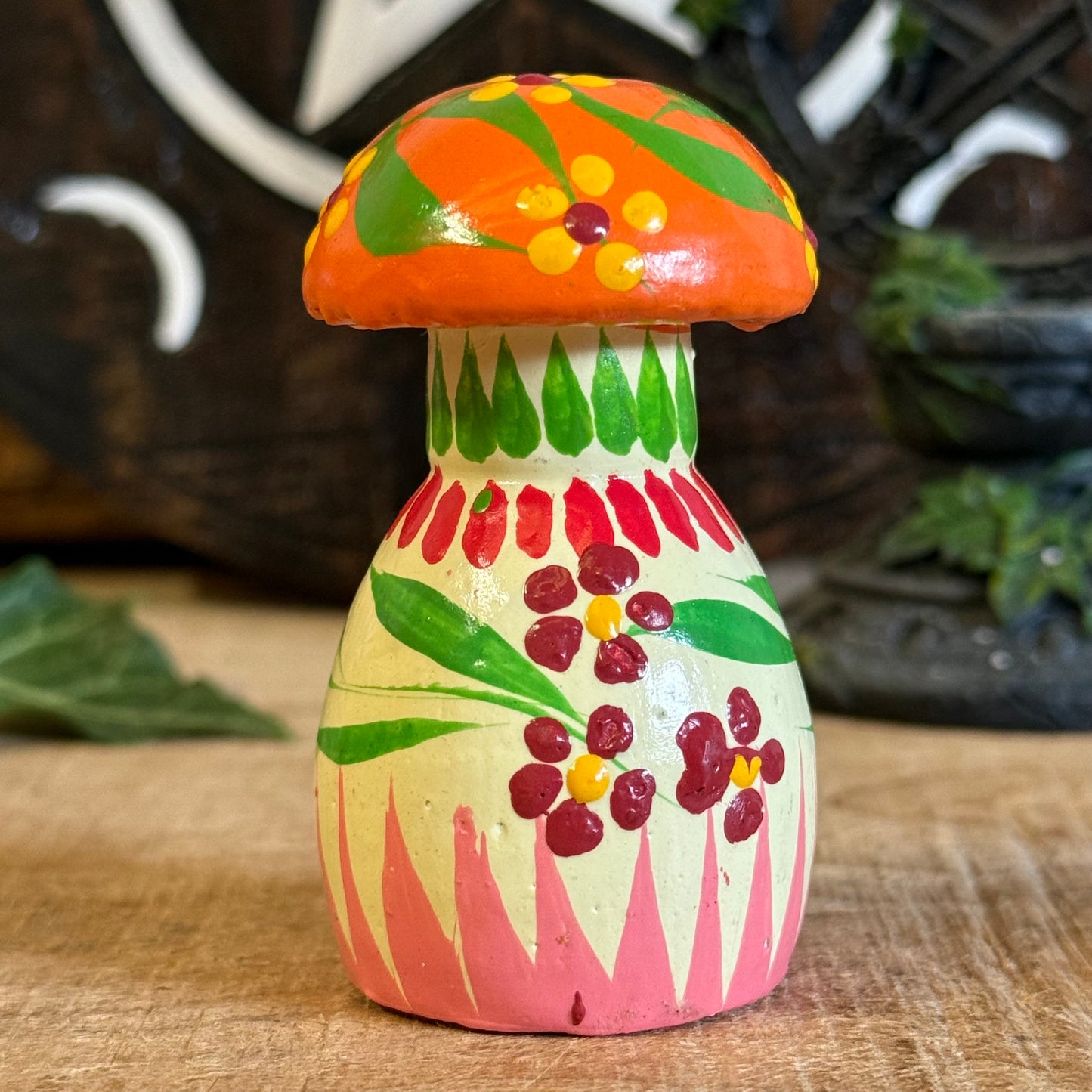 Colorful mushroom-shaped ceramic toy on a wooden surface with a blurred background