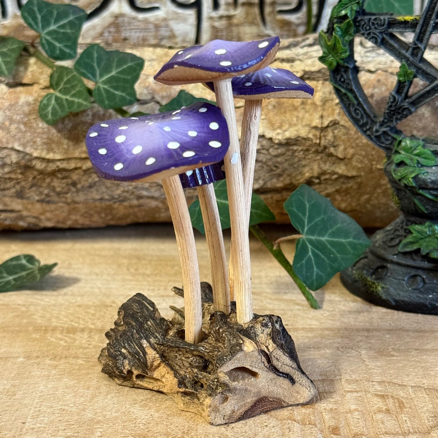 Hand carved purple wooden mushrooms on rustic base. Perfect fairy home or cottage-style décor, adding whimsical woodland charm to any space.