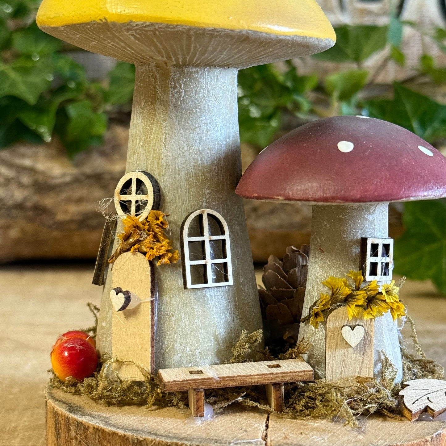 Wander into a whimsical woodland with our Folk Art Mushroom Two Cottages (Tall) — a delightful pair of hand painted fairy houses inspired by rustic village life and the charm of springtime meadows. Each tall mushroom cottage is adorned with bright folk art patterns, floral details, and earthy tones that bring a sense of storybook enchantment to your home.
