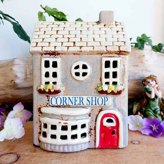 At the heart of an enchanted street stands the Corner Shop, its windows glowing softly as if lit by unseen hands. This Shudehill Village Pottery tealight house is crafted from ceramic to capture the quiet magic of village life, where candlelight flickers like whispered exchanges between worlds.