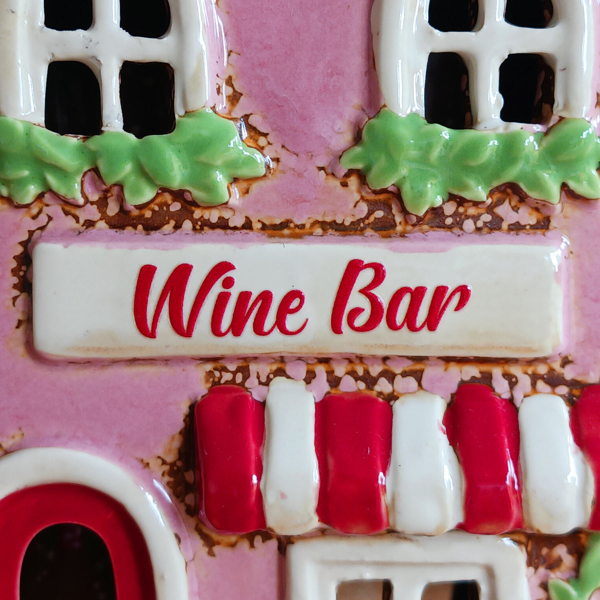 Bring the charm of a quaint village high street into your home with this delightful Village Pottery Wine Bar Tealight Holder. Hand-crafted from ceramic and beautifully hand-painted, this charming miniature wine bar is packed with character and intricate details.