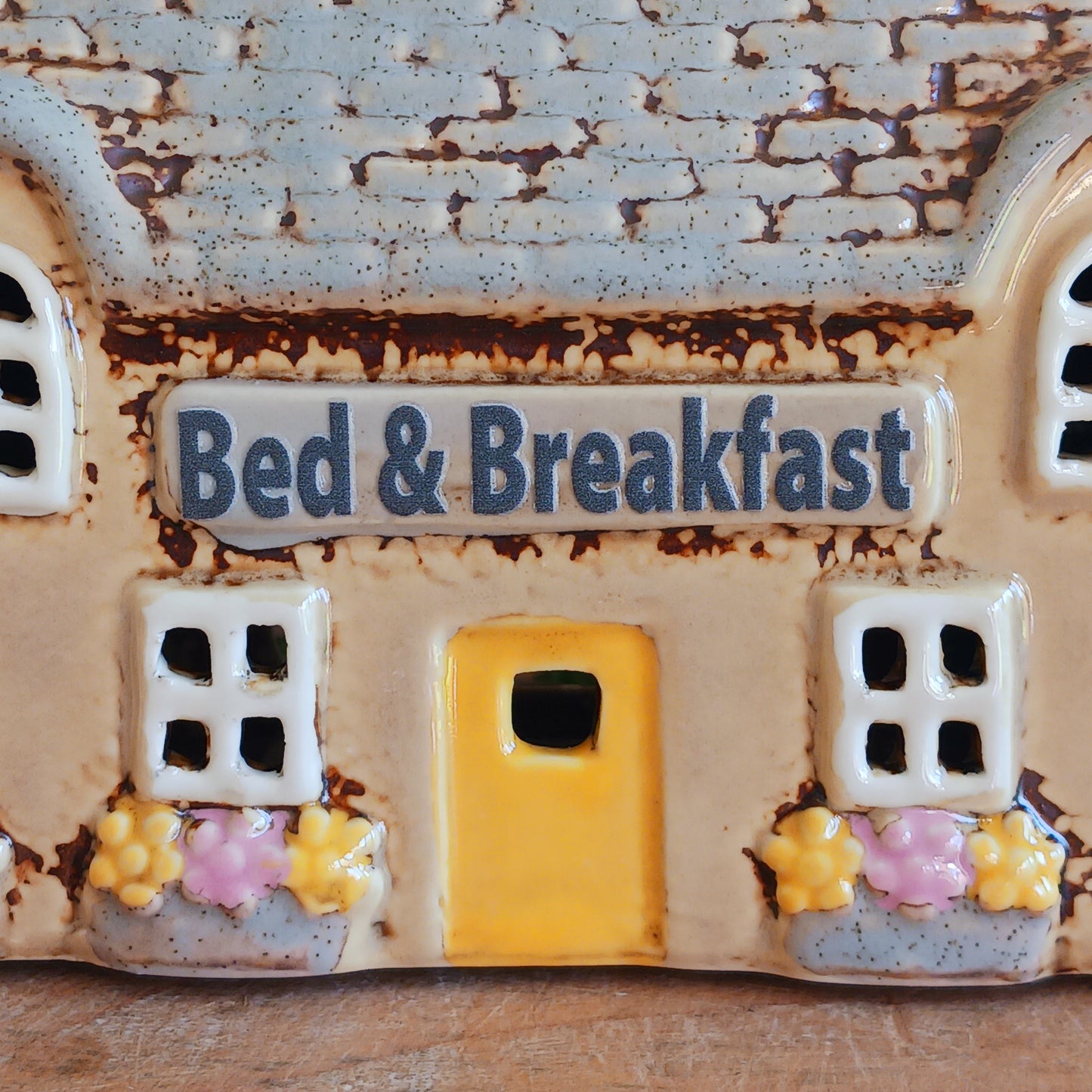 A welcoming glow awaits within this Village Pottery Bed & Breakfast Tealight House, where candlelight flickers through tiny windows like a hearth lit for wandering souls. Crafted from ceramic, this charming inn captures the spirit of an enchanted village, inviting warmth, stillness, and quiet magic into your space.