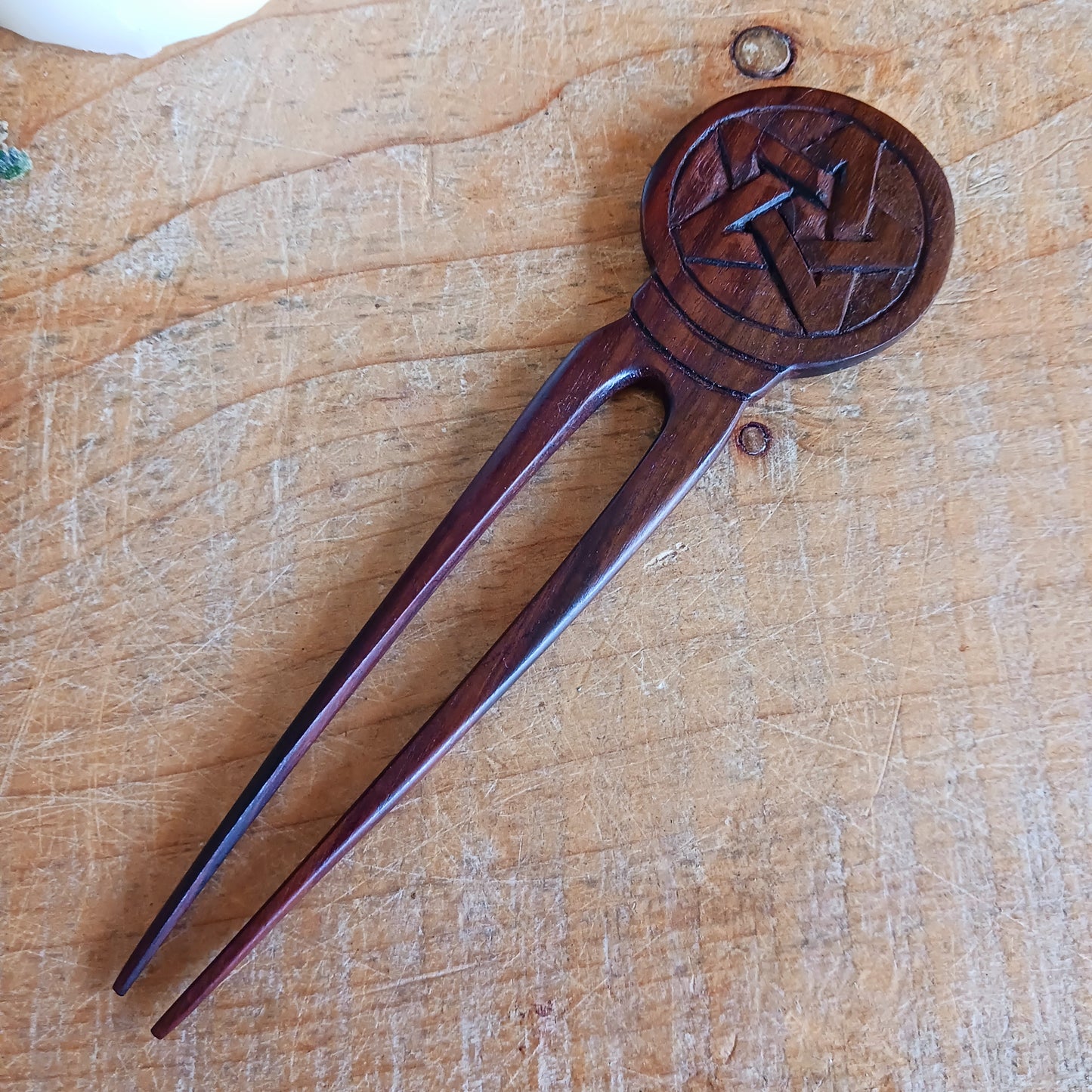 Slip into a realm of whispered enchantments with the Pentacle Design Hair Fork. Handcrafted from rich, dark natural wood, its elegant two-pronged form tucks smoothly into your hair, offering both beauty and balance.