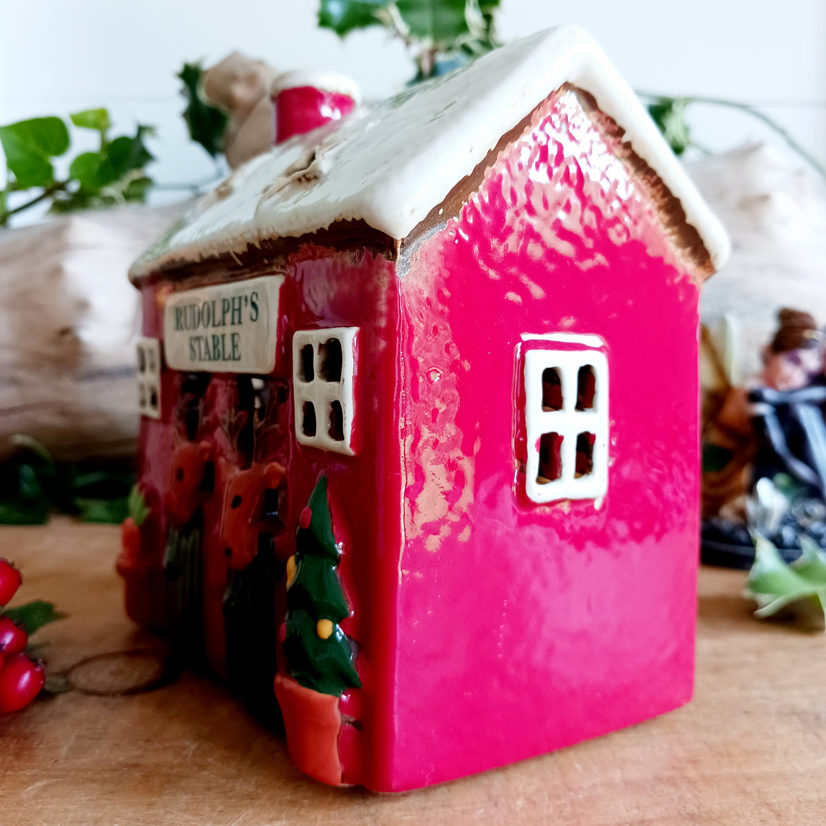 Bring a touch of festive village charm to your home with the Village Pottery Xmas Rudolph’s Stable Tealight Holder. This delightful ceramic Christmas decoration is designed as a quaint little stable, featuring a snowy roof, traditional green doors and charming reindeer detailing.