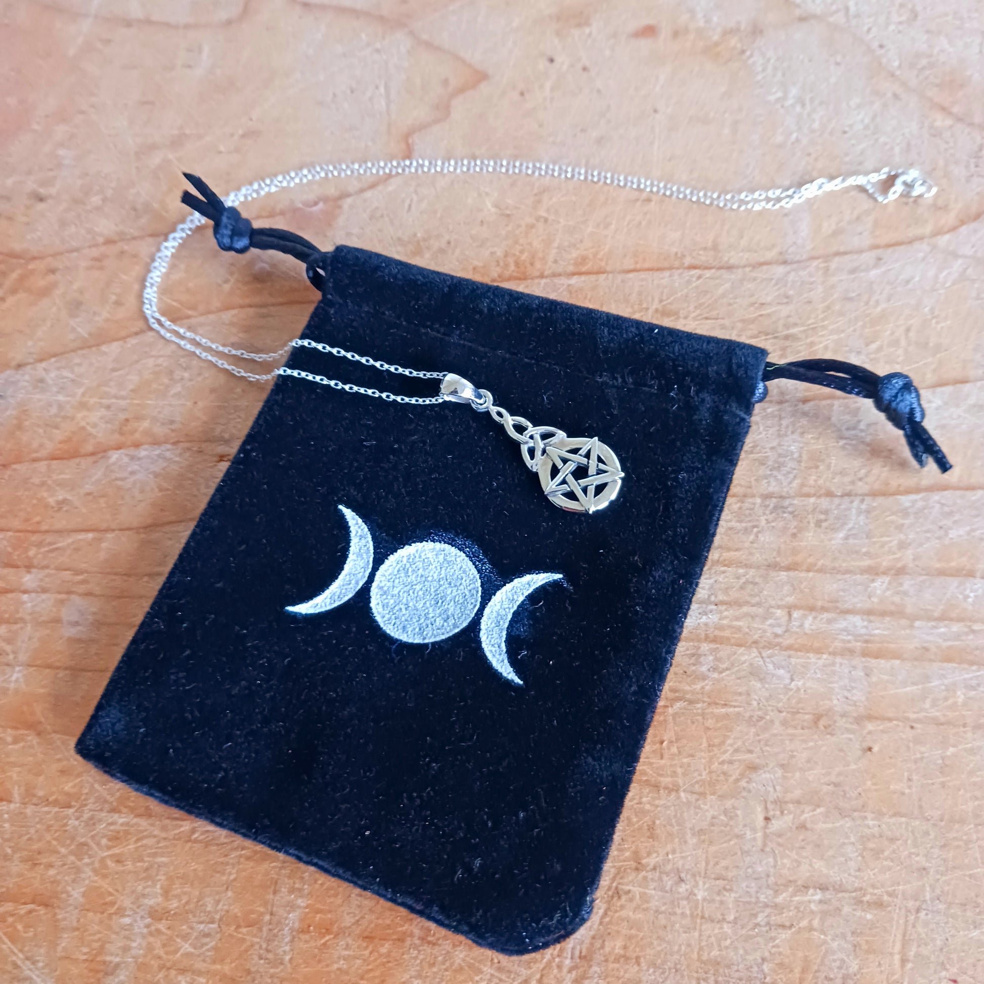 This beautiful pendant creates a significant and luminous amulet. The design is vertically oriented, featuring two distinct but harmoniously linked symbols. At the base is a prominent, circular Five-Pointed Star (Pentacle/Pentagram), the classic symbol of protection and the balanced harmony of the five elements.