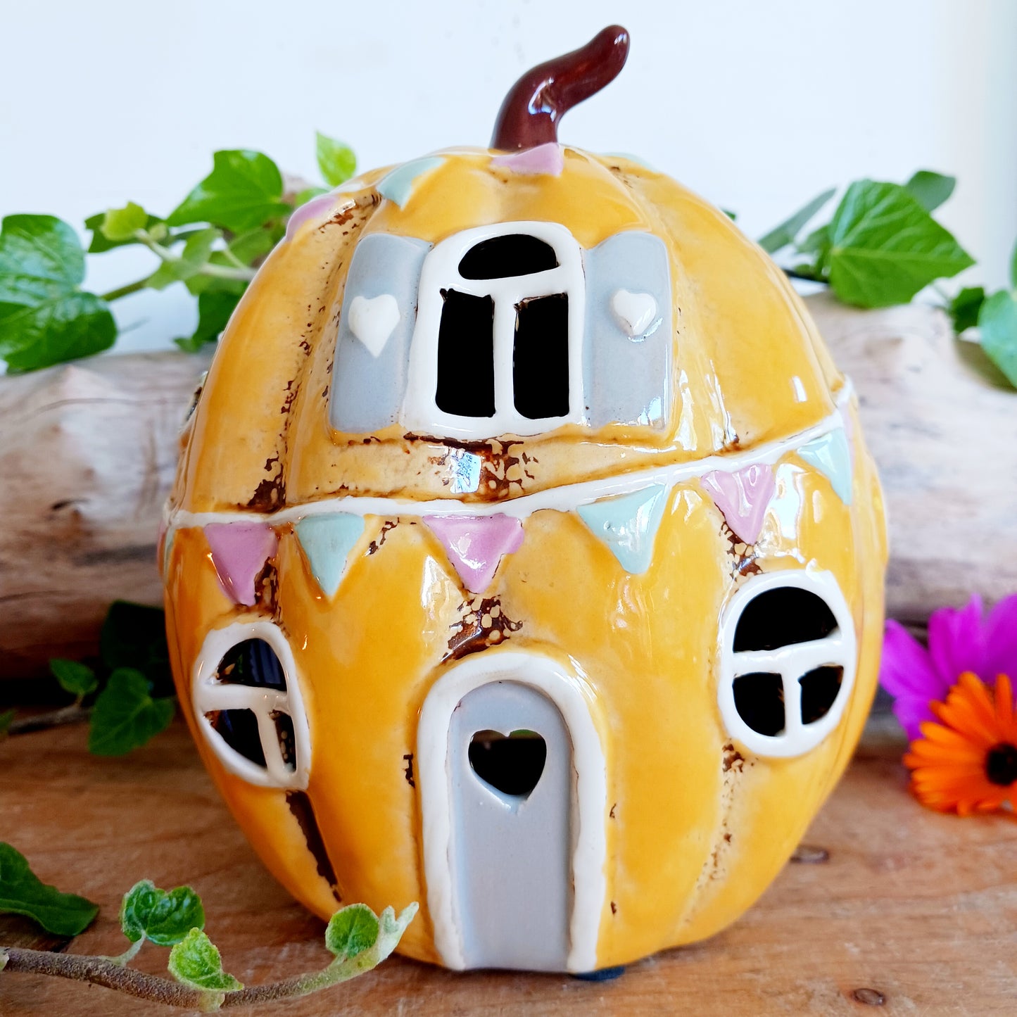 Invite a little woodland wonder into your home with the Village Pottery Pumpkin House Tealight Holder, a delightful hand-painted creation in a soft yellow ceramic glaze. Measuring 17 x 13 x 11 cm, this fairy-tale pumpkin cottage glows beautifully when lit, filling your space with warmth, light, and a touch of enchantment.