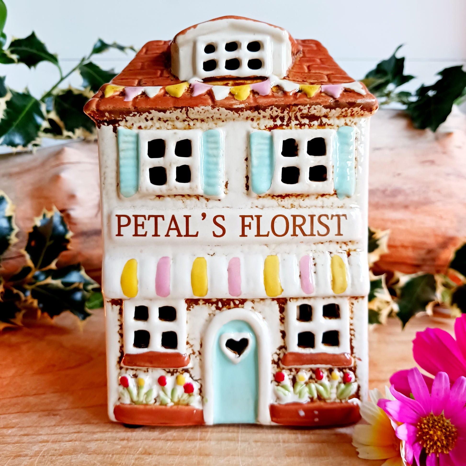 Handcrafted in the Village Pottery workshop, this Florist Tealight Holder is a true collectible from the Shudehill Collection. Made from fine ceramic with intricate detailing, it captures the nostalgic charm of a festive florist shop in a snow-dusted winter village scene.