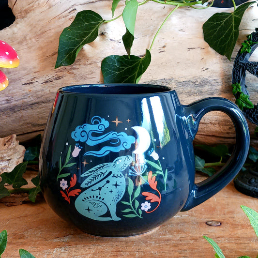 Bring a little magic to your morning with this enchanting Mystical Midnight Hare Ceramic Mug. Featuring a charming hare gazing up at a glowing moon beneath a star-filled night sky, this beautifully rounded mug is perfect for anyone who loves mystical, celestial and nature-inspired designs.