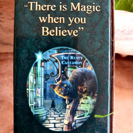 Bring a touch of magic into your home with the enchanting Rusty Cauldron Incense Burner by renowned fantasy artist Lisa Parker. Featuring her iconic artwork, this beautifully crafted piece captures a mystical feline perched atop a barrel outside the legendary Rusty Cauldron, while another curious cat watches the magical high street unfold behind.