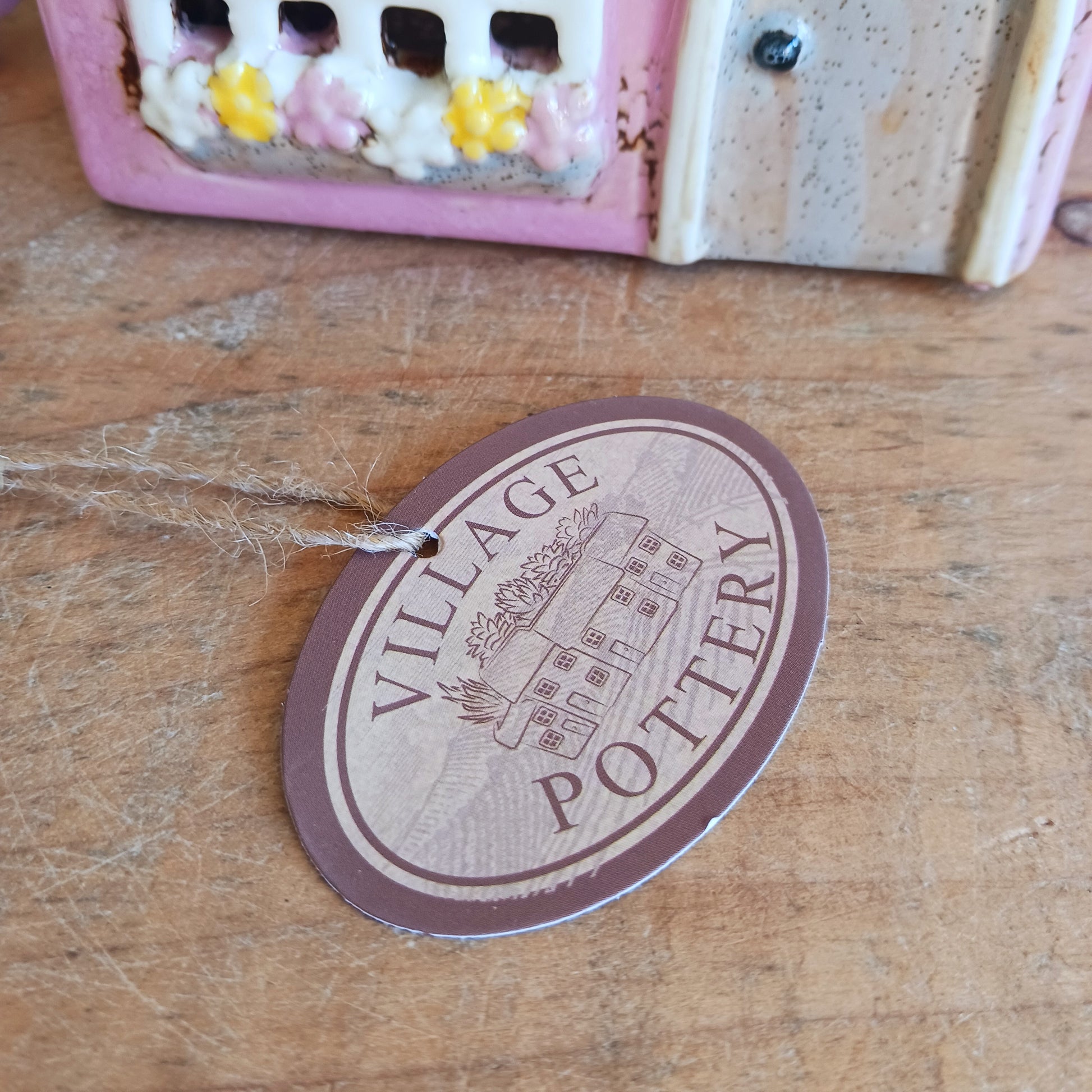 A comforting glow brews within the Coffee Pot Shop, where candlelight flickers like steam rising from a warm cup in a quiet enchanted village. This Shudehill Village Pottery tealight house is crafted from ceramic, casting a soft, golden light through its windows to create a scene of calm and gentle magic.