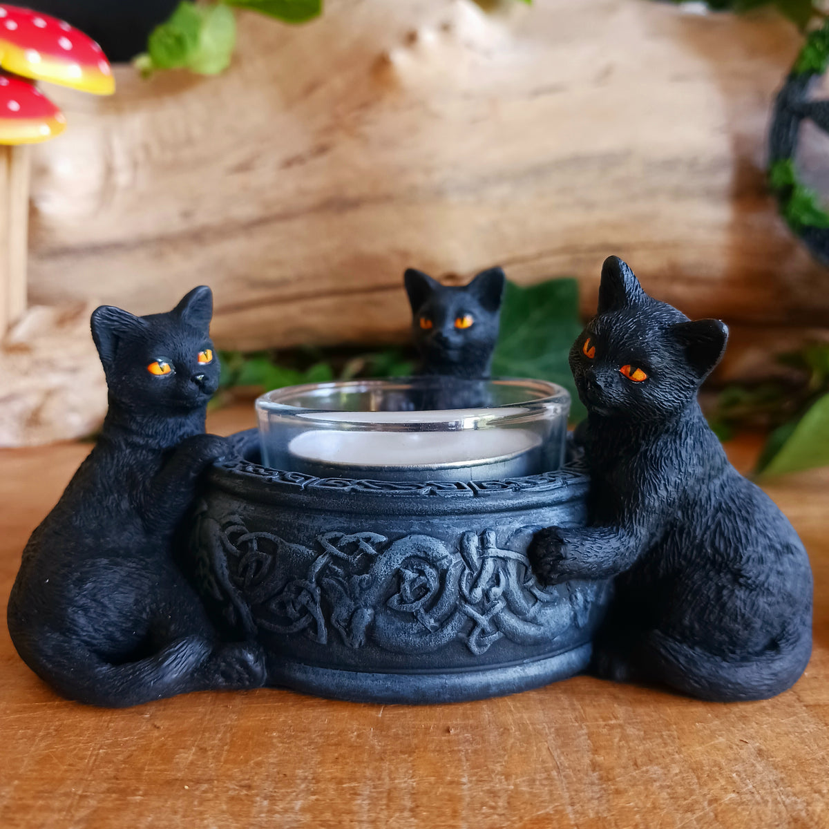 Bring a touch of playful witchcraft and gothic charm into your home with the Familiar Trio Tea Light Holder. Featuring three mischievous black cat familiars gathered around a central tealight, this enchanting candle holder creates a warm and atmospheric glow with plenty of magical character.