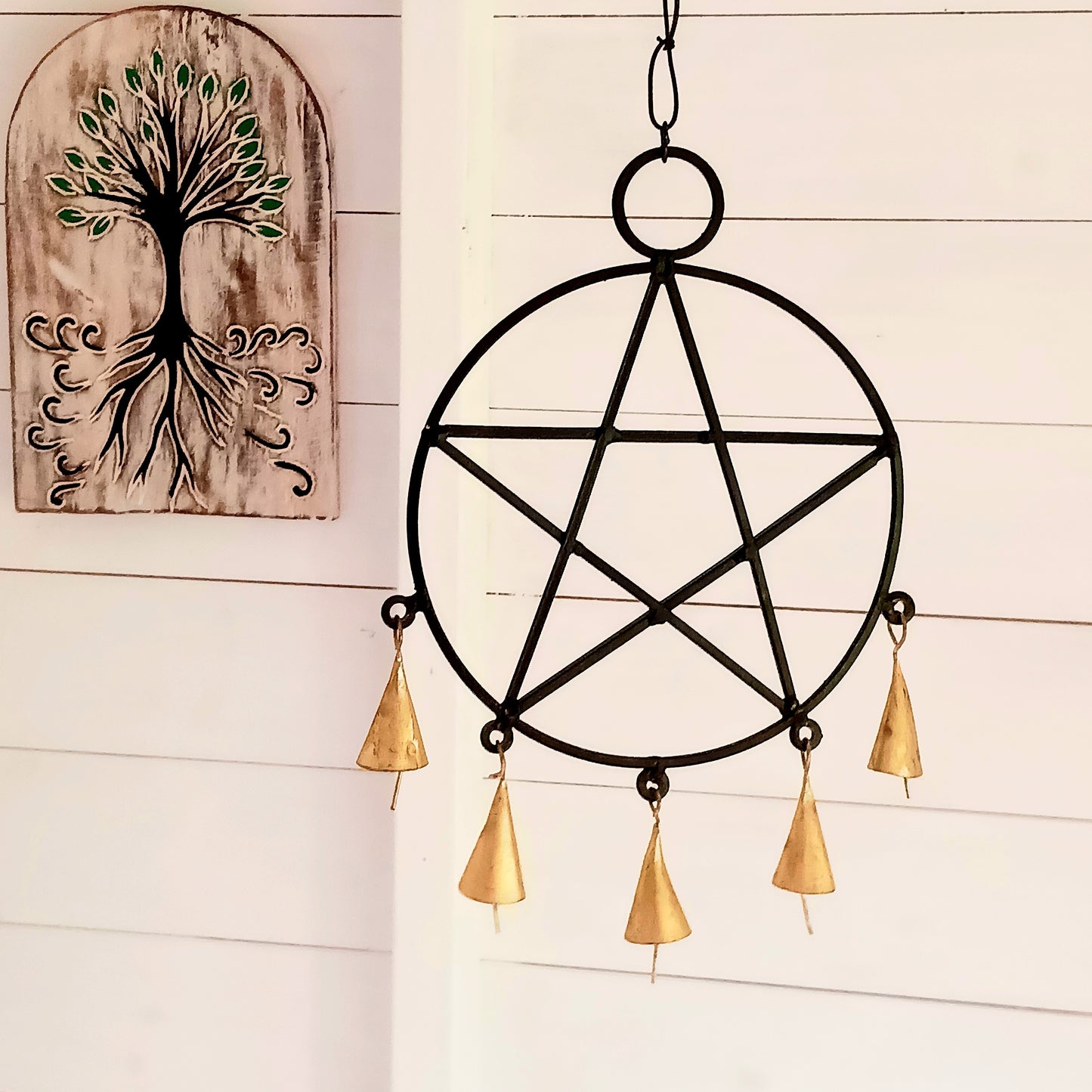 Bring mystical charm and a touch of gothic elegance to your space with this striking black metal pentagram decoration. Crafted with intricate detail, the five-point star hangs gracefully from a sturdy chain and features five fine brass bells that chime softly with movement. Perfect for pagan, Wiccan, or boho-inspired décor, this piece can be hung indoors or outdoors, adding both beauty and symbolism to your home. Ideal for altars, spiritual spaces, or as a unique wall hanging.