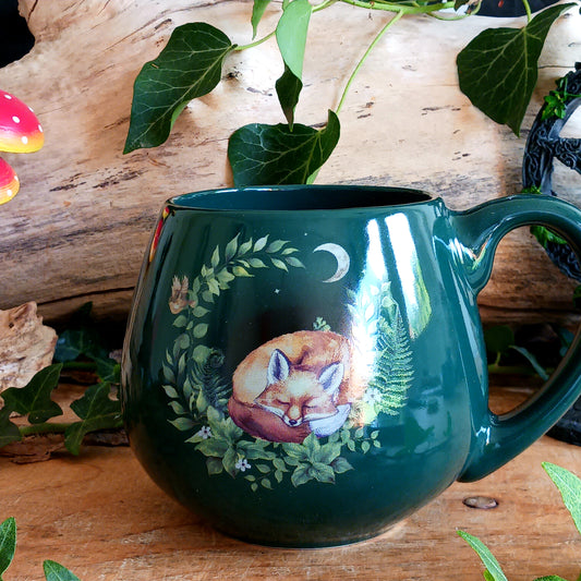 Start your day with a cosy cup of tea, coffee or hot chocolate in this charming Sleeping Fox in the Forest Ceramic Mug. Featuring a peaceful fox curled up among the trees, this delightful woodland-inspired mug brings a touch of nature and countryside charm to your kitchen.